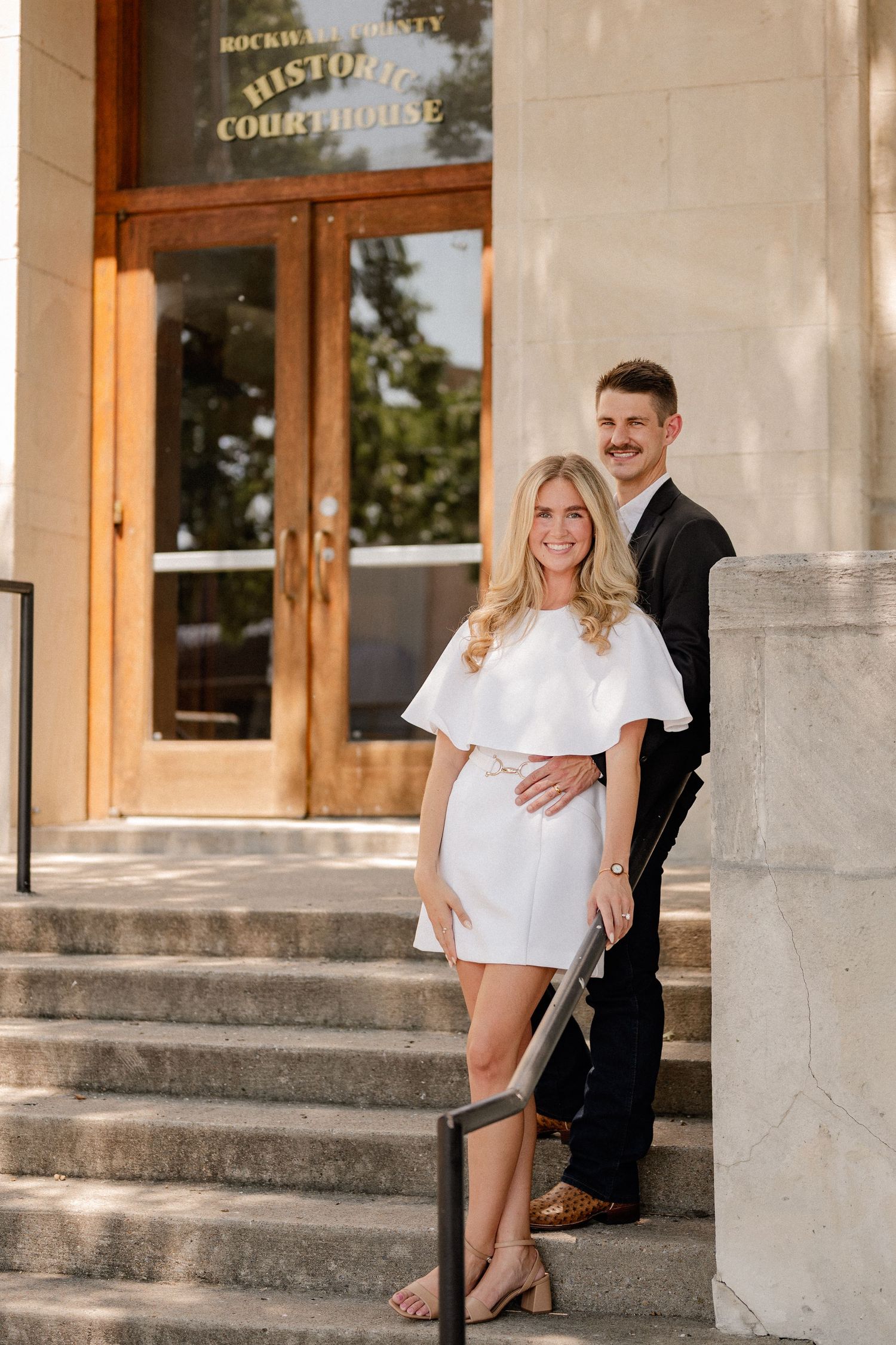 Married couple posed down a staircase outside of downtown Rockwall courthouse during elopement wedding photo session