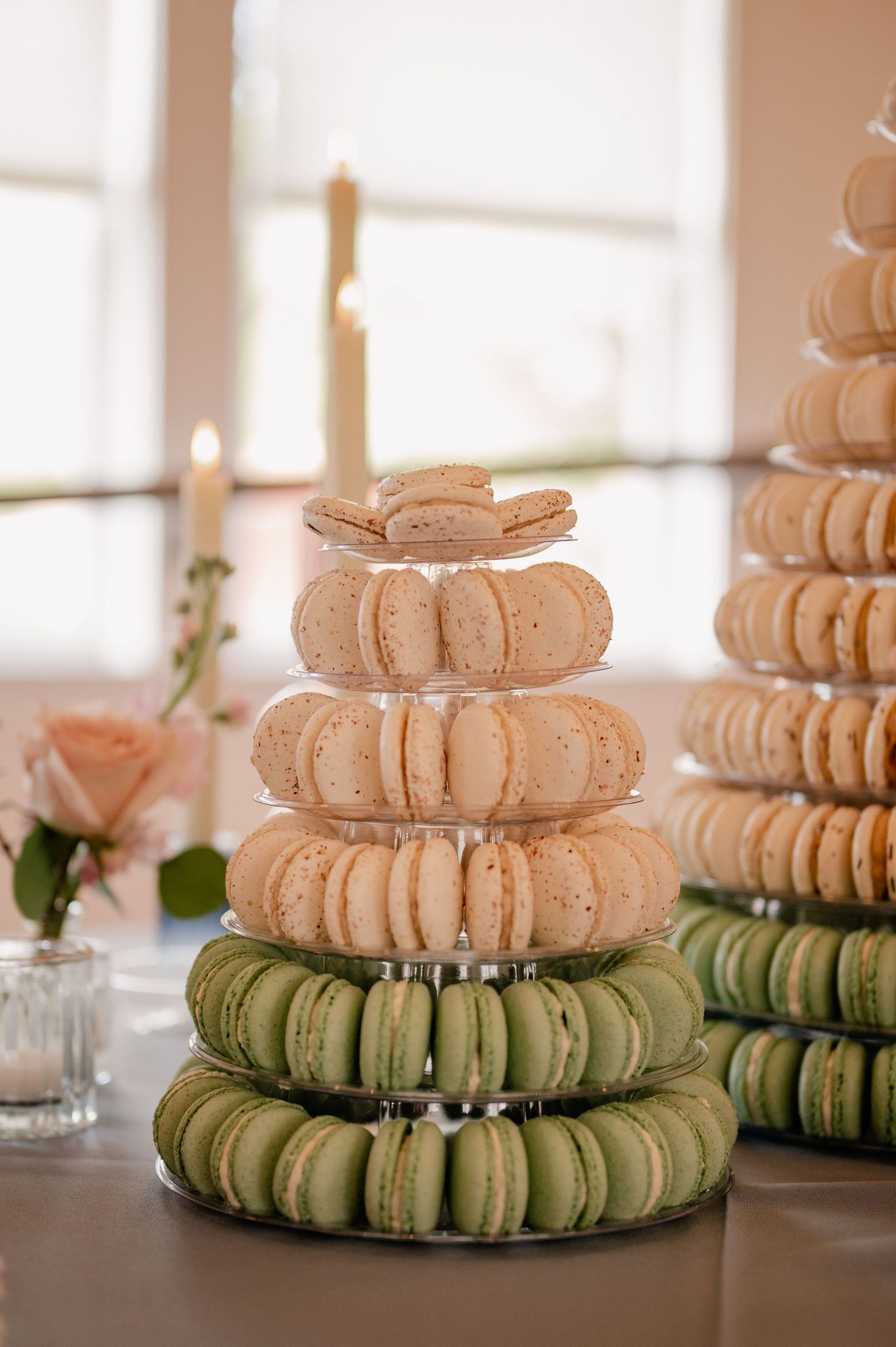 Tower of colorful macarons stacked in ombre pattern from white to mint green with pink rose accent at Dallas, TX wedding
