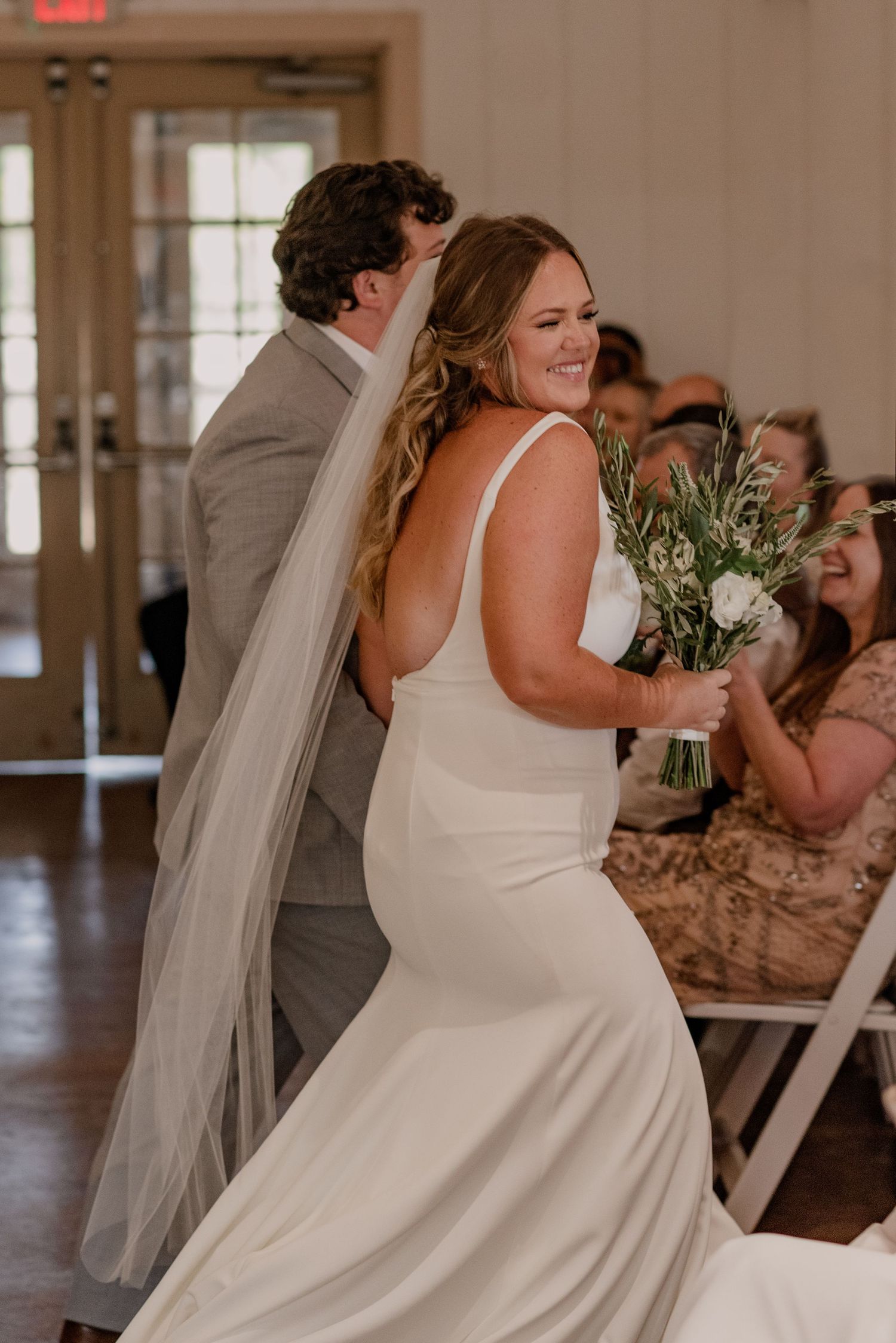 A joyful wedding celebration moment captured inside an elegant white reception space.