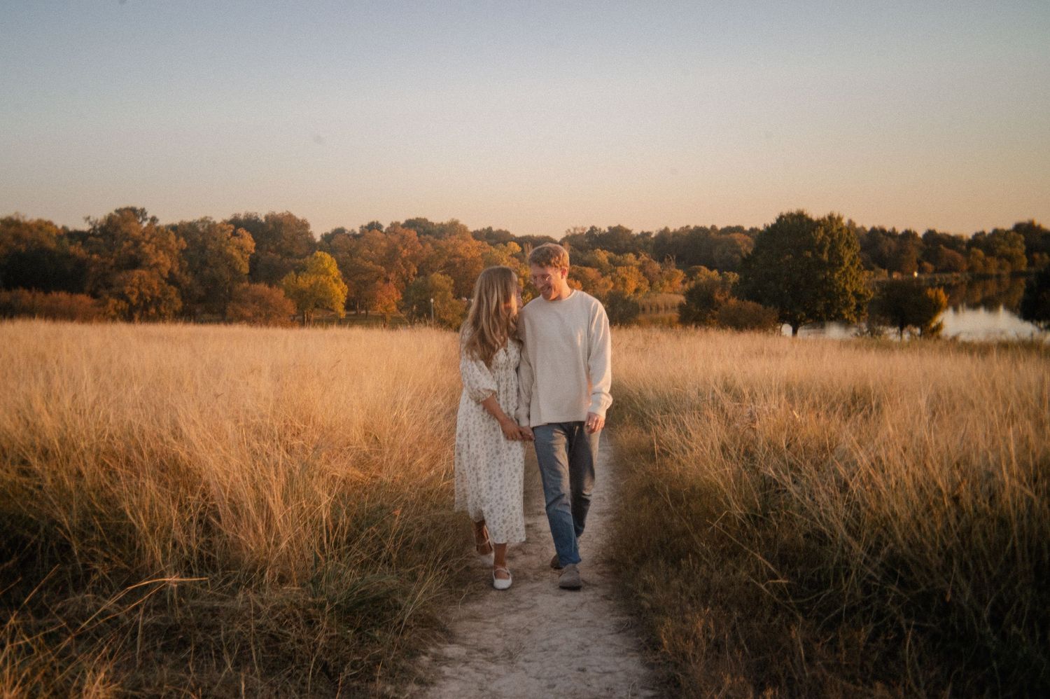 Candid film photo of engaged couple during fall engagement session in tall grass at golden hour in East Dallas, Texas