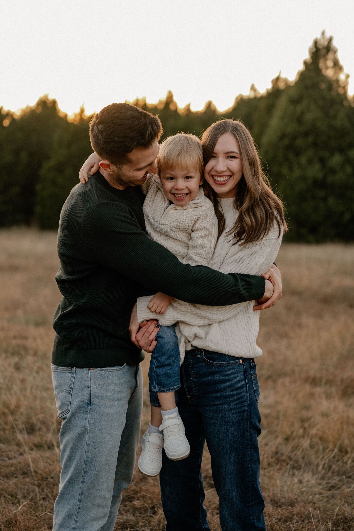 Family candidly bear hugging in an open tree-lined field in Sunnyvale, Texas for a winter family photo session