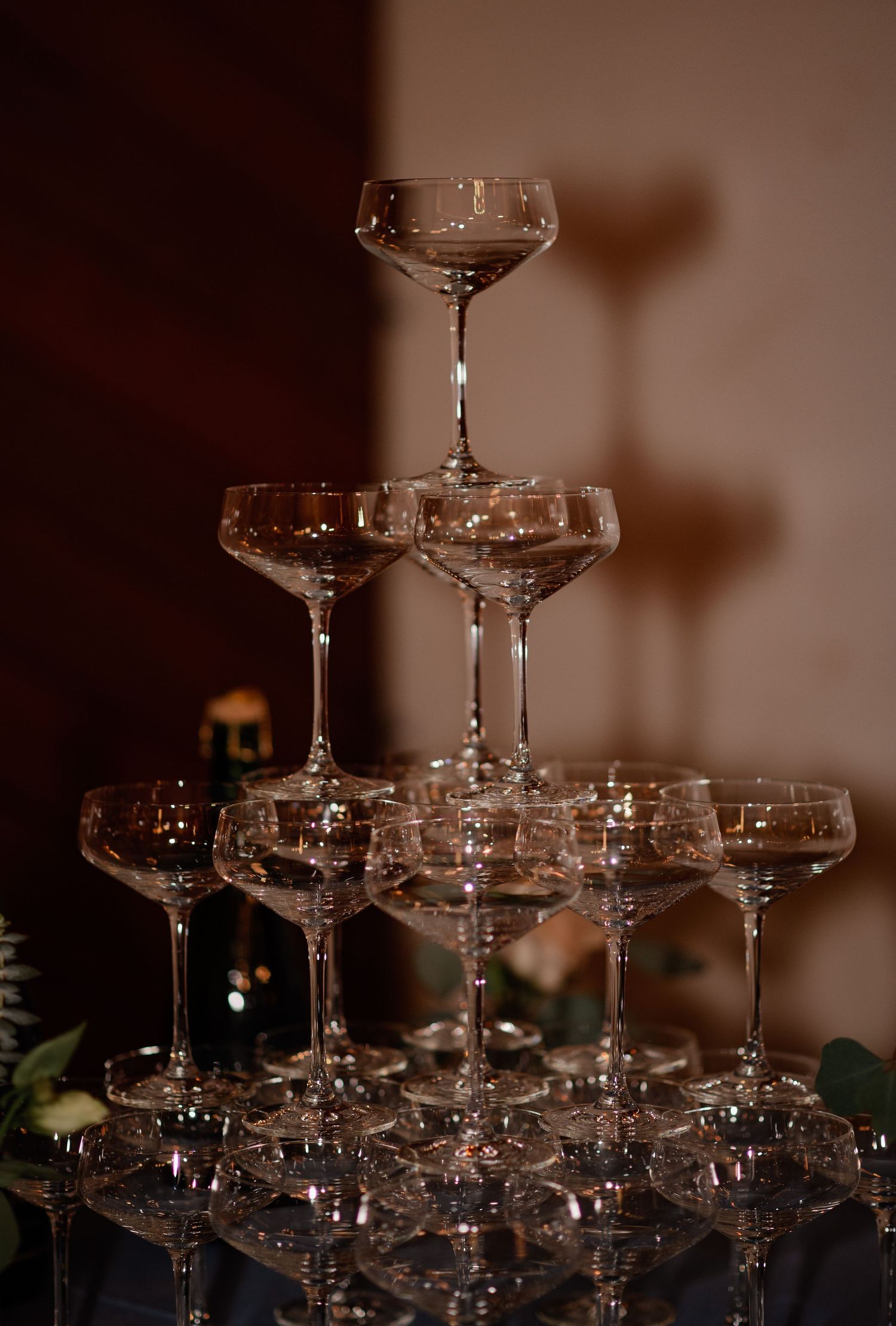 Elegant champagne tower with crystal glasses catching dramatic lighting.