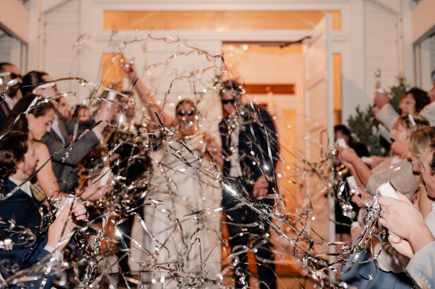 Joyful exit from wedding reception with guests popping streamers outside of Bishop Arts venue in Dallas, Texas