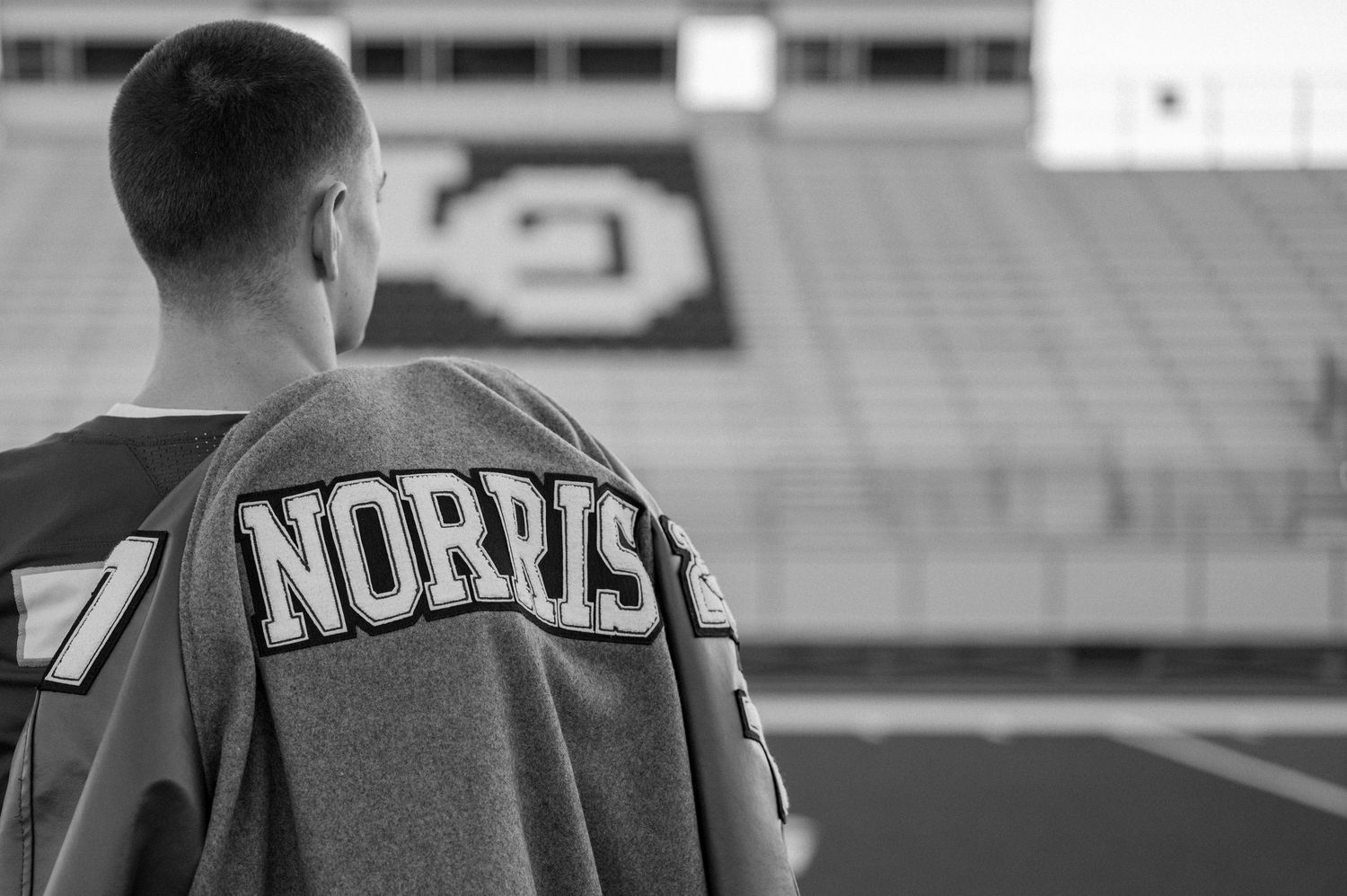 Senior boy seriously posing in a football stadium for his summer senior photo session in Lone Oak, Texas