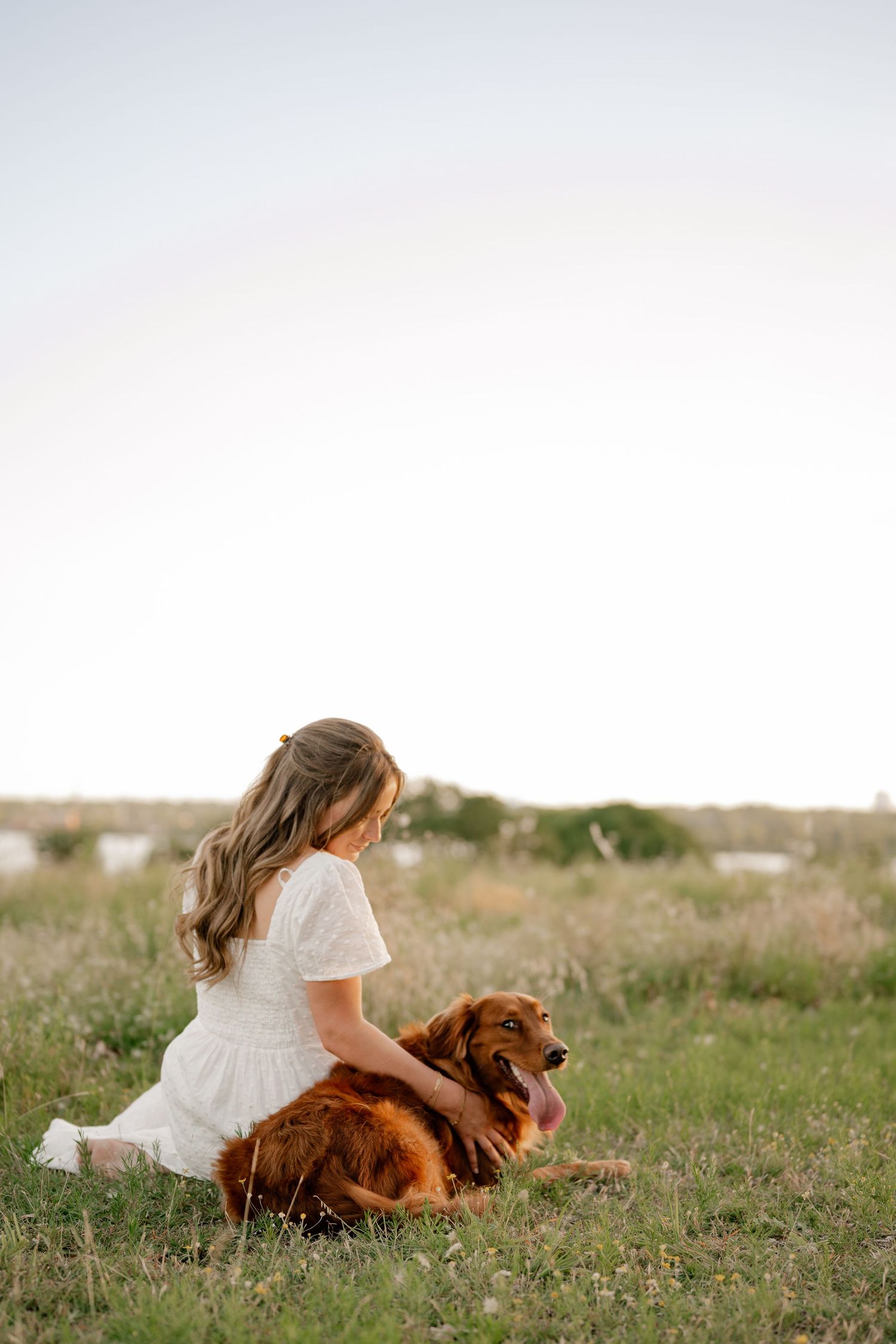 Candid lifestyle portrait of a girl and her dog sitting in a field overlooking White Rock Lake in East Dallas, Texas