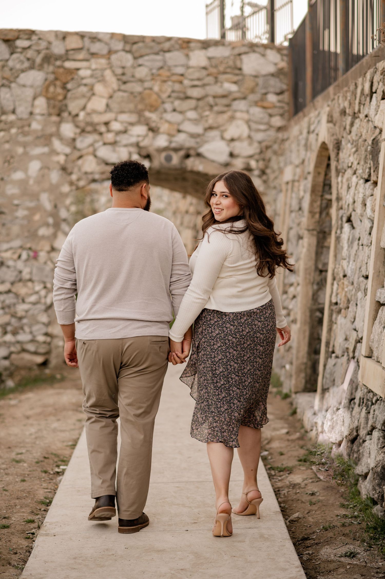 Couple candidly holding hands walking through the Croatian inspired Adriatica Village for a Fall couples photo session in McKinney, Texas