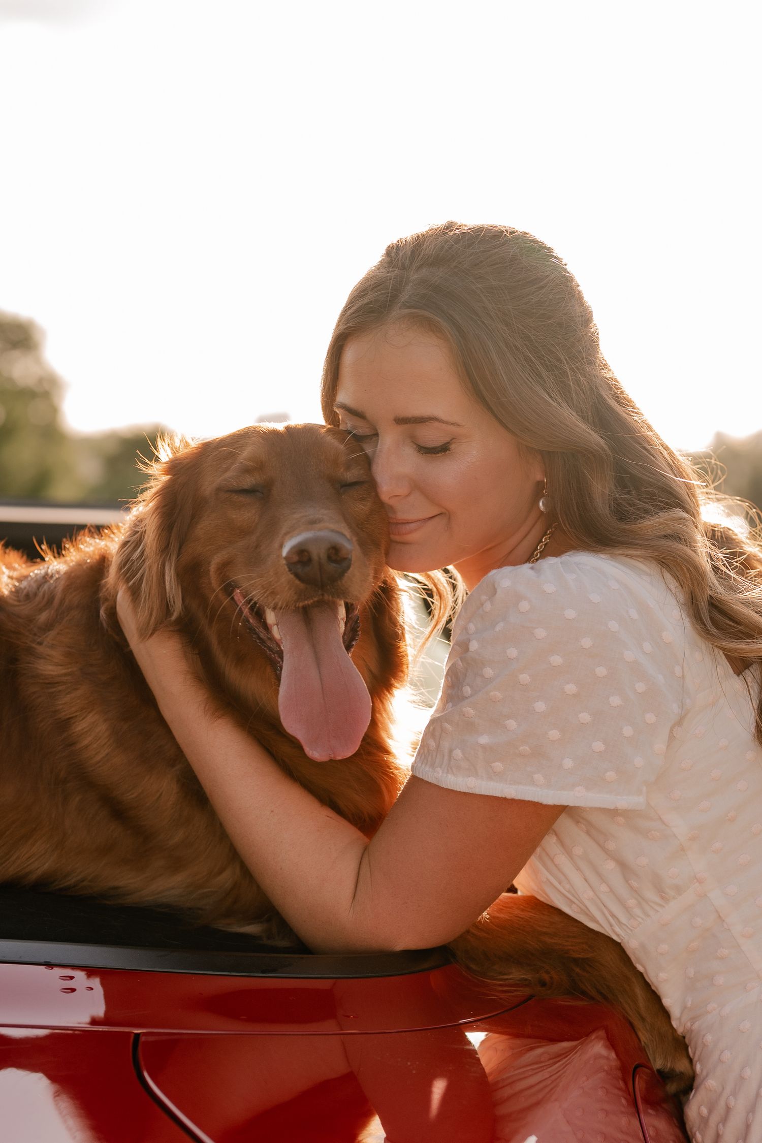 Vintage style portrait of a girl and her dog embracing off the back of her red convertible overlooking White Rock Lake in East Dallas, Texas