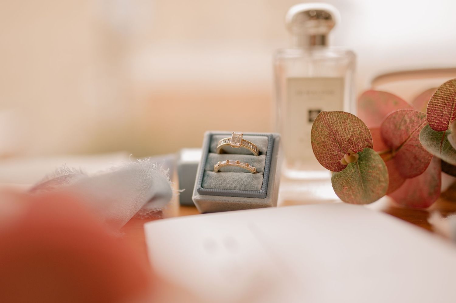 Wedding rings displayed artistically with perfume bottle and dried flowers