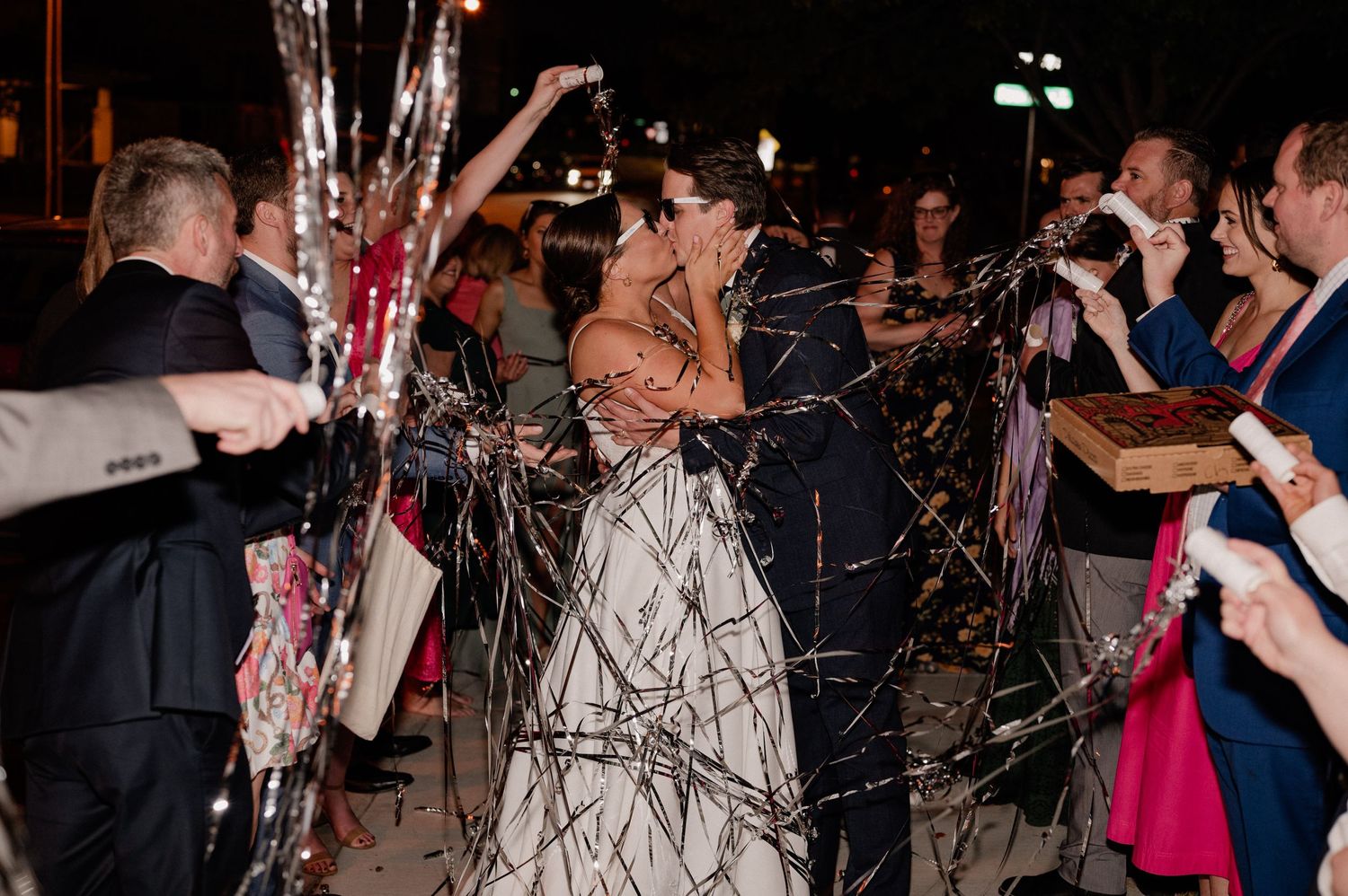 Guests line pathway with streamers as wedding couple makes their grand exit of Bishop Arts venue in Dallas, Texas