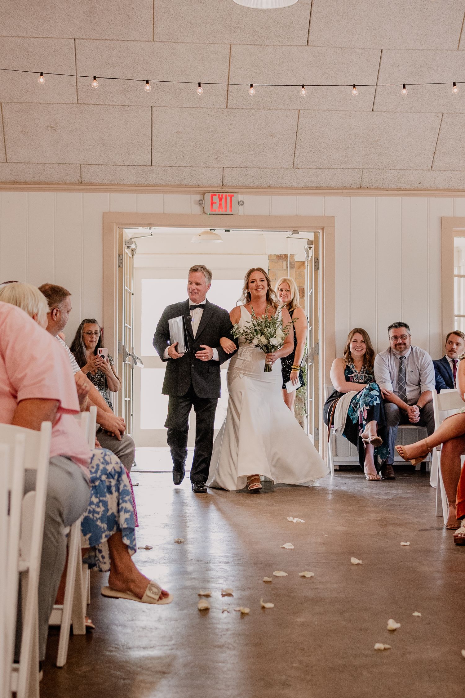Wedding party dancing and celebrating in a bright indoor venue with concrete floors.