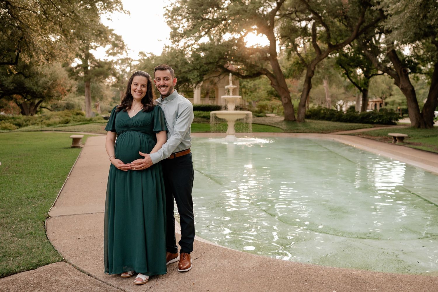 Couple standing in front of a water feature at Flippen Park in Dallas for their Spring maternity photo session