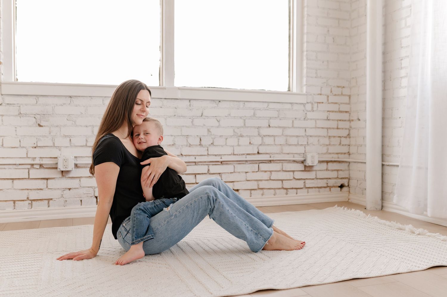 Candid lifestyle photo showing an affectionate embrace between mother and son in a bright indoor studio in Dallas, Texas