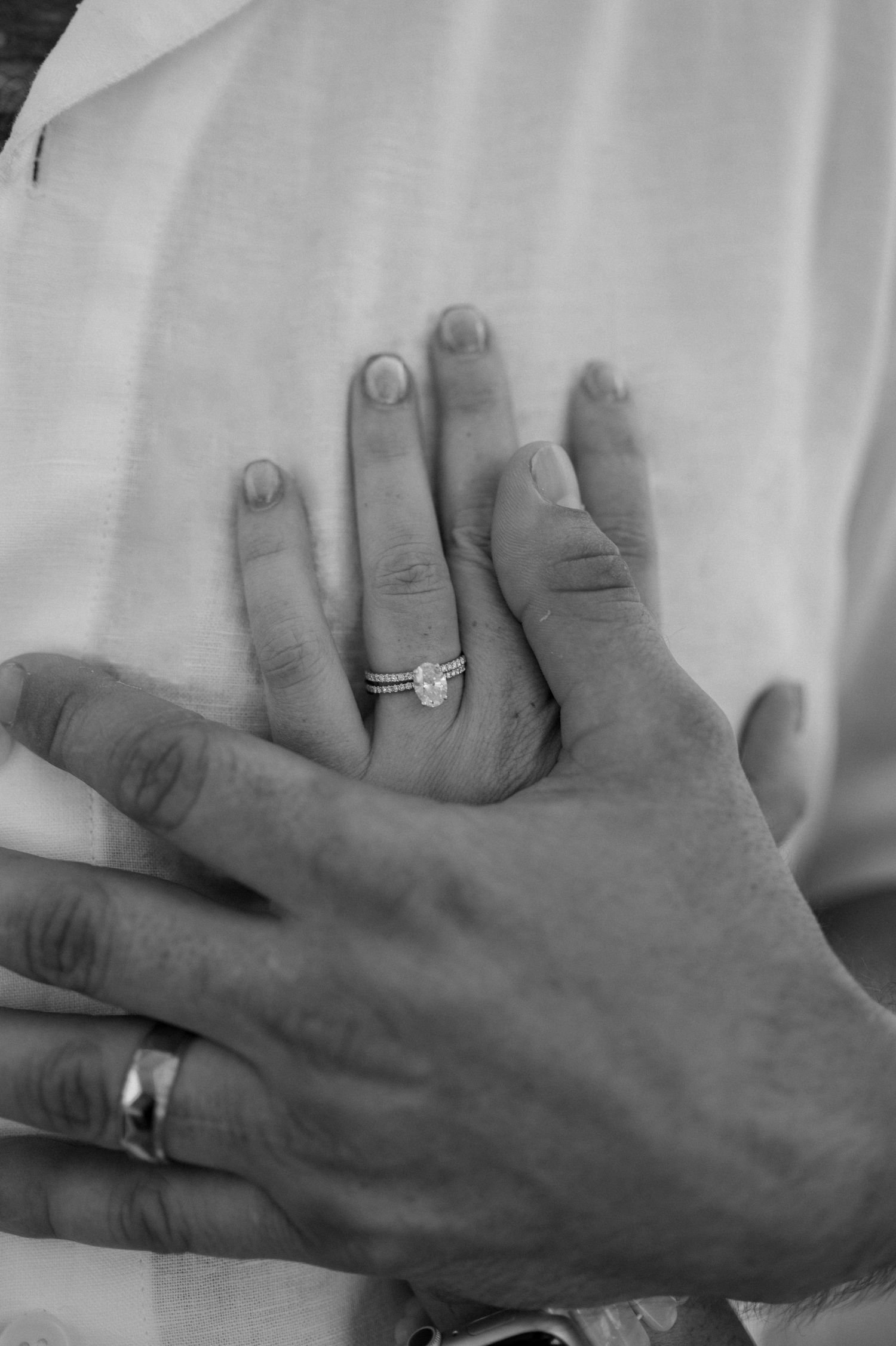 Close up black and white photo of married couple's hands embracing with a focus on the wedding rings