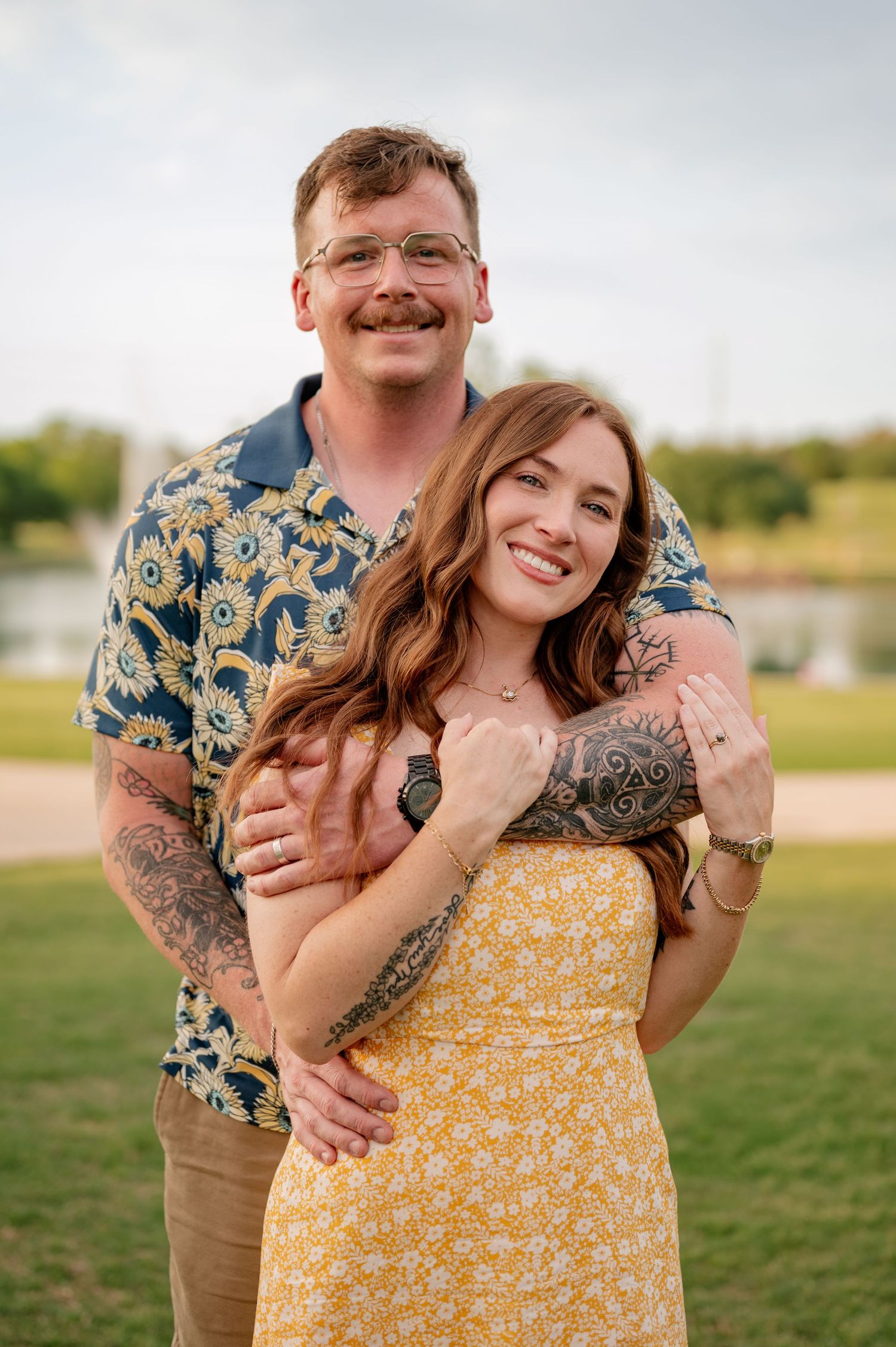 Married couple posing for Spring family photos in vivid colors at large park with water feature in Rockwall, Texas