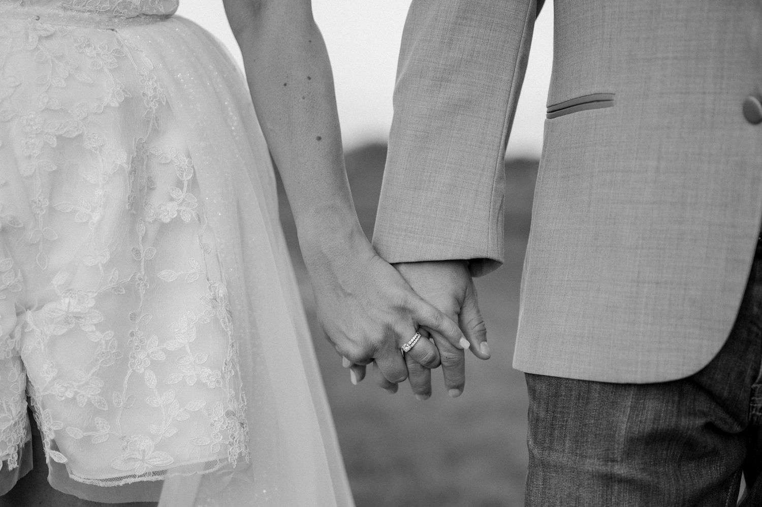 A close up detail of a bride and groom holding hands during wedding couple portraits in outdoor field near Rockwall, Texas
