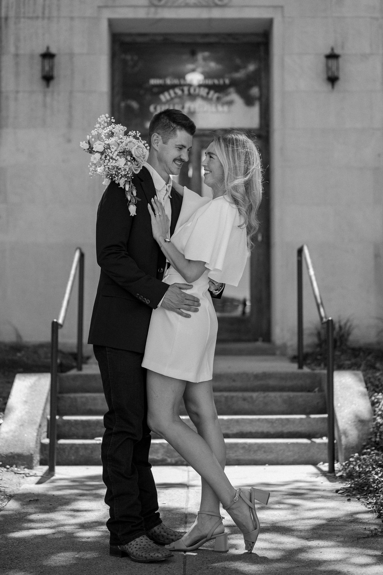 Black and white intimate photo of married couple outside of downtown Rockwall courthouse during elopement wedding photo session