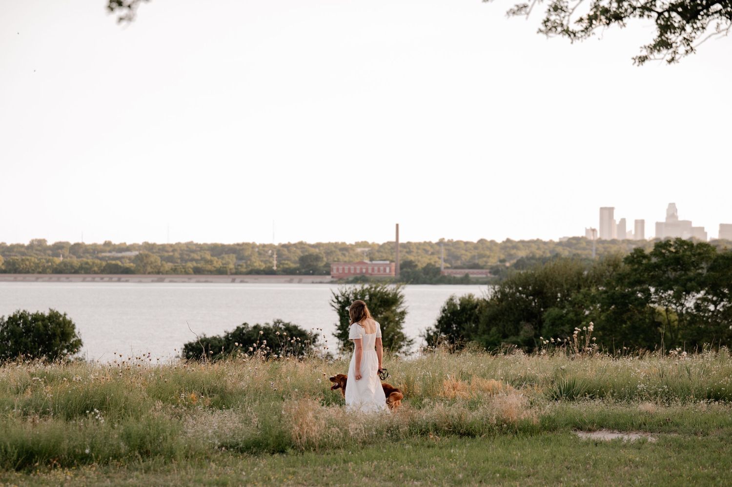 Candid lifestyle portrait of a girl and her dog walking in a field overlooking White Rock Lake in East Dallas, Texas