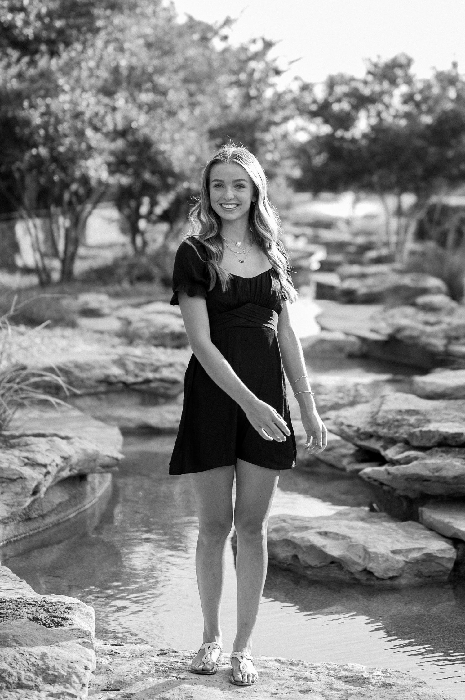 Senior girl casually posing in a natural spring and rocks for a summer senior photo session in Frisco, Texas