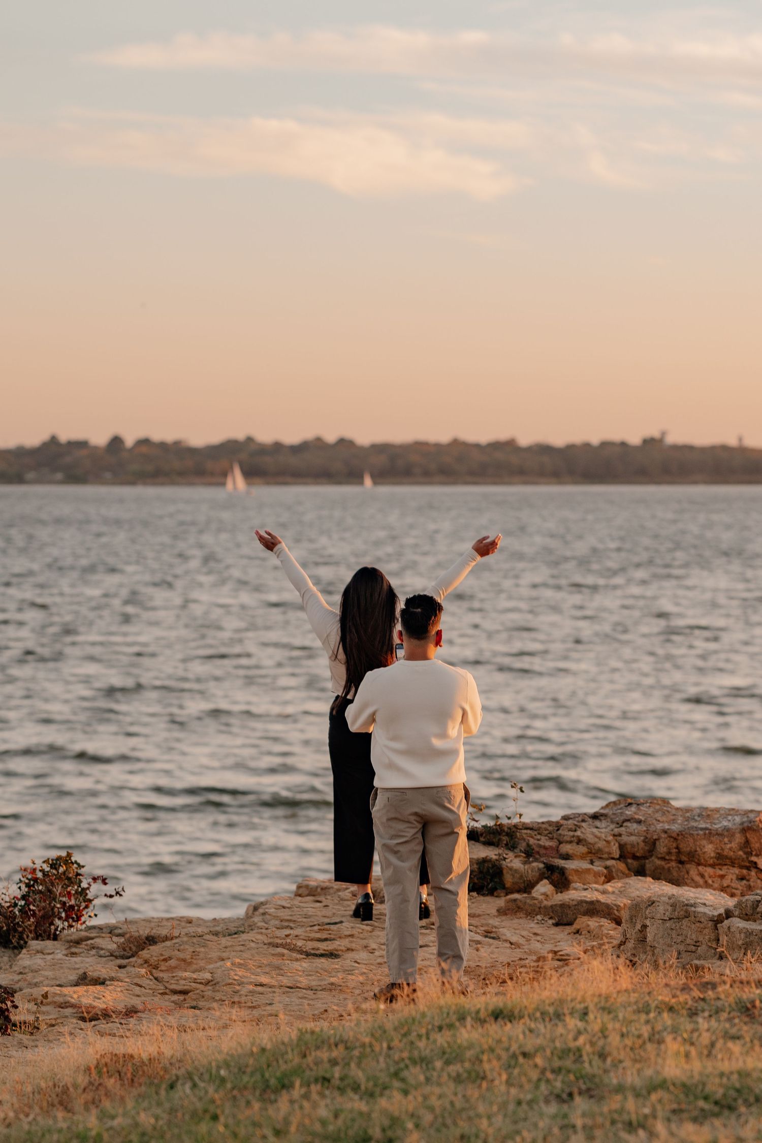 An excited man awaits the turn of his girlfriend as he prepares to propose to her overlooking a lake in Grapevine Texas at golden hour