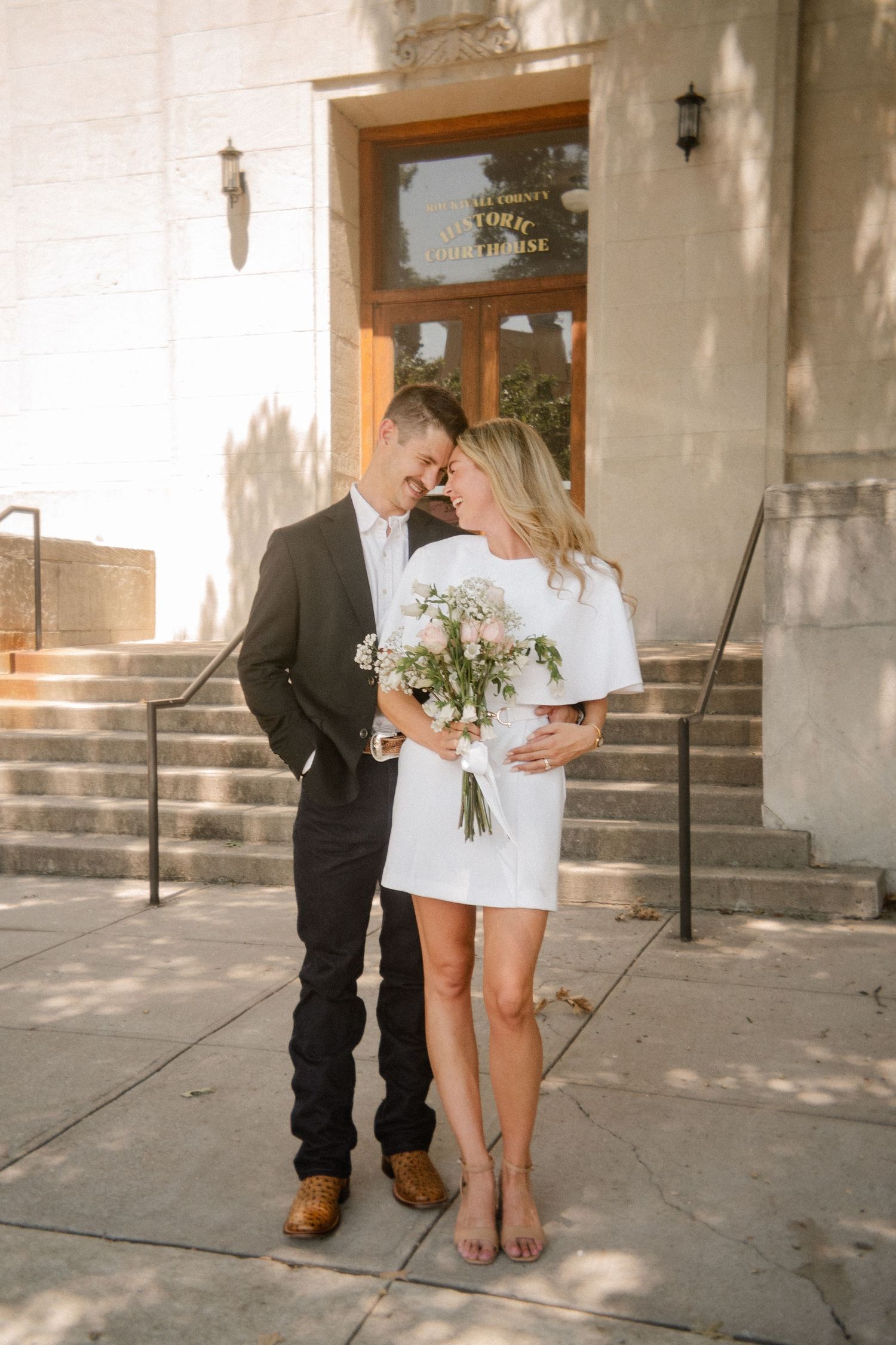 Film photo of couple posing with heads together outside of the downtown Rockwall courthouse during elopement wedding photo session
