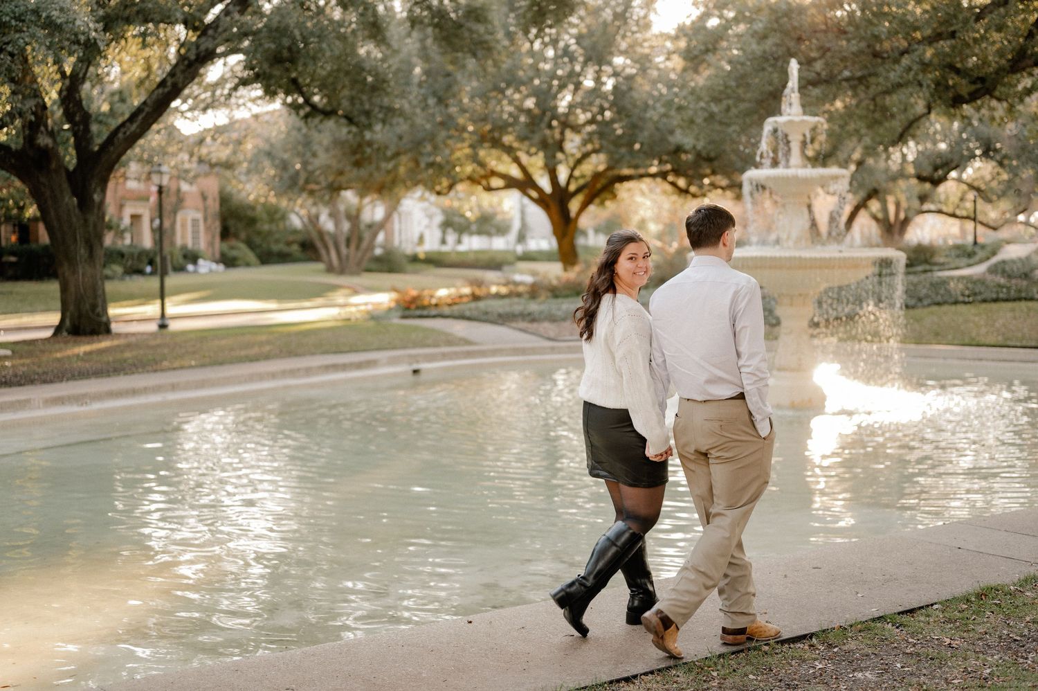 Couple walking in front of a water feature at Flippen Park in Dallas for their winter engagement photo session
