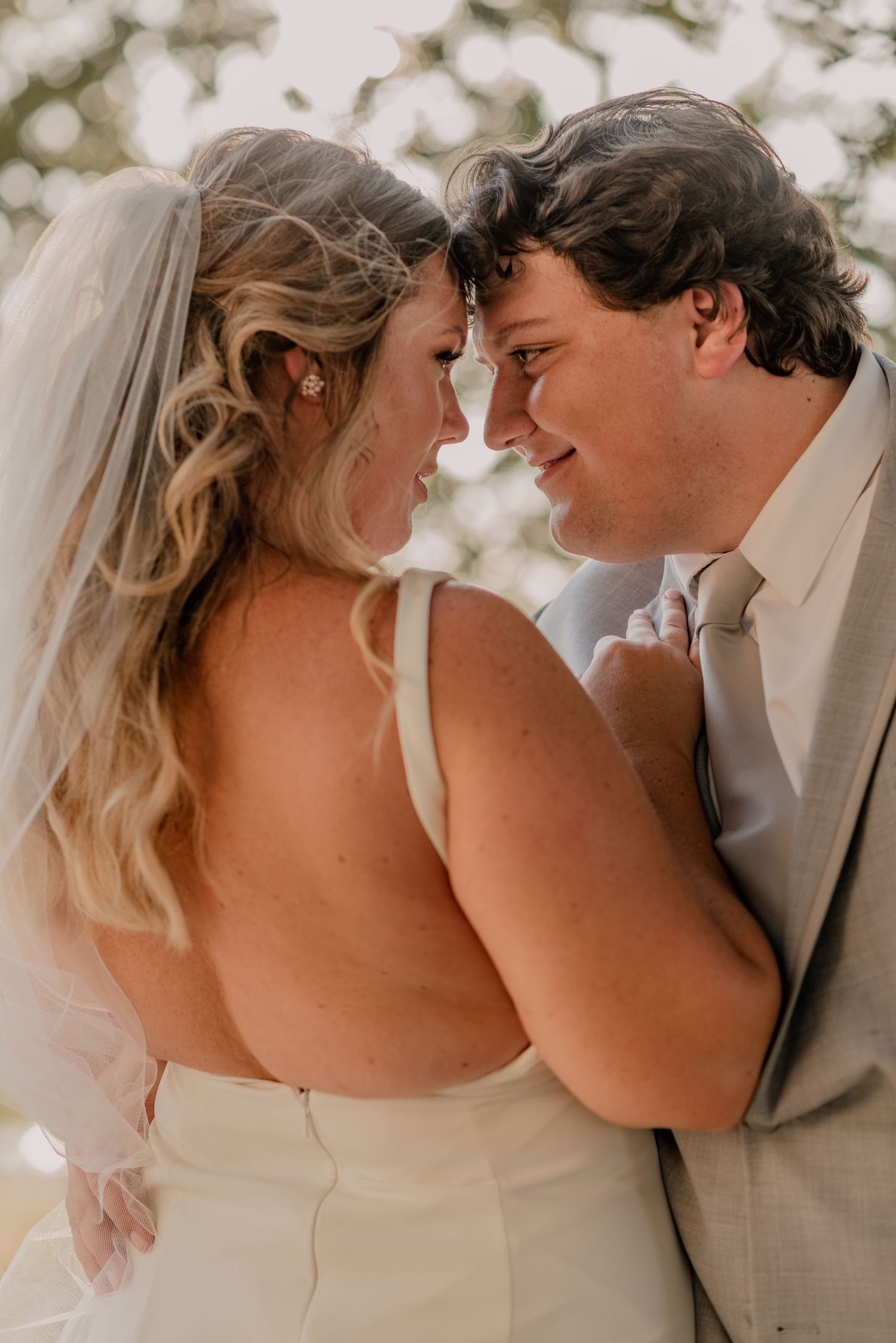 Romantic close-up of couple in wedding attire sharing intimate moment outdoors.