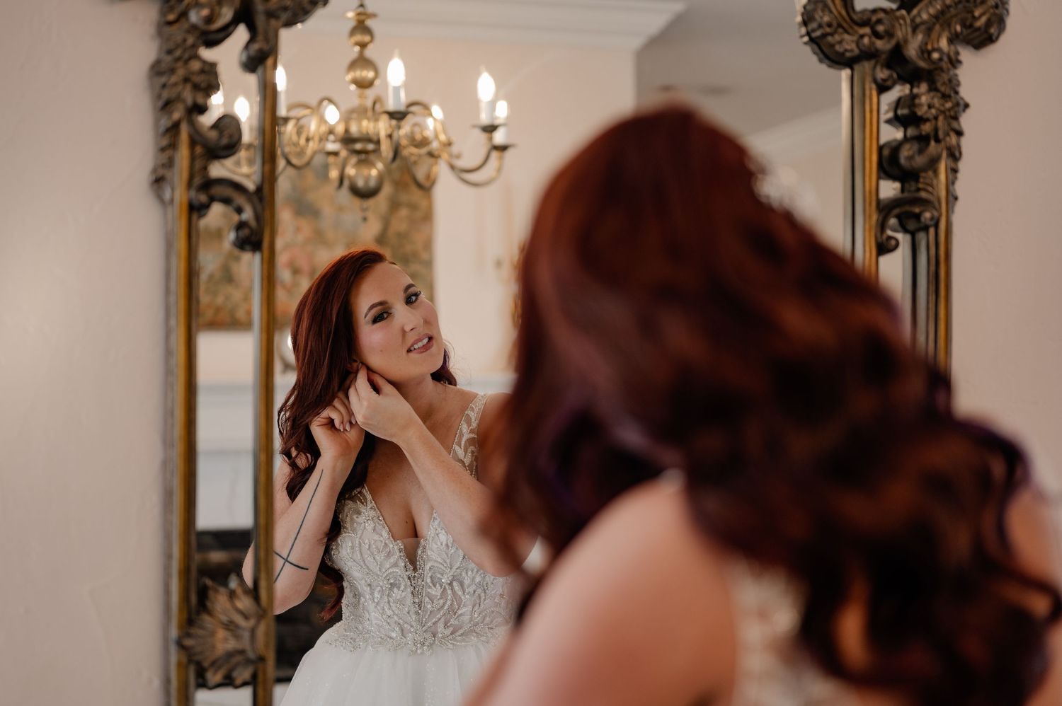 Bride candidly putting on wedding jewelry in a mirror at her winter wedding in Fort Worth, Texas