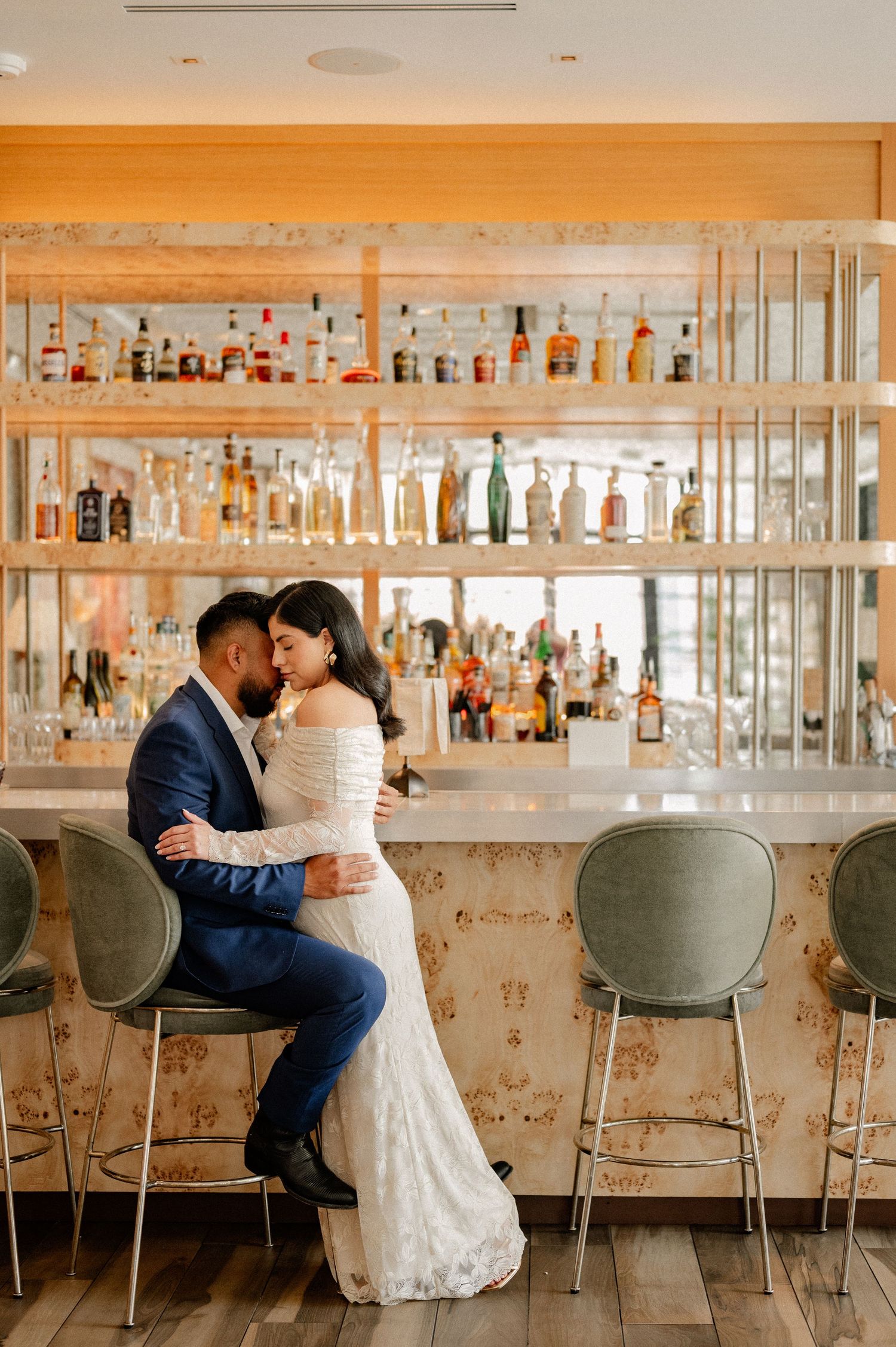 Wide shot of Couple intimately embracing during engagement session on a rooftop venue in downtown dallas in front of large upscale bar