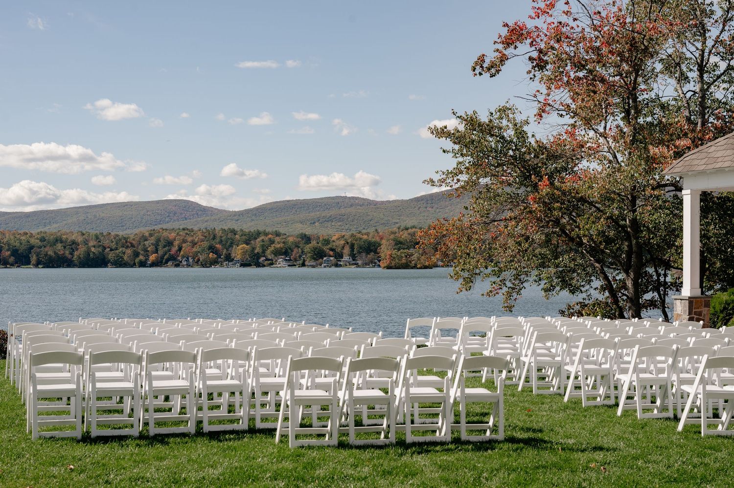 White chairs arranged for an outdoor wedding ceremony overlooking a scenic lake and mountain landscape in the Berkshires, Massachusetts.