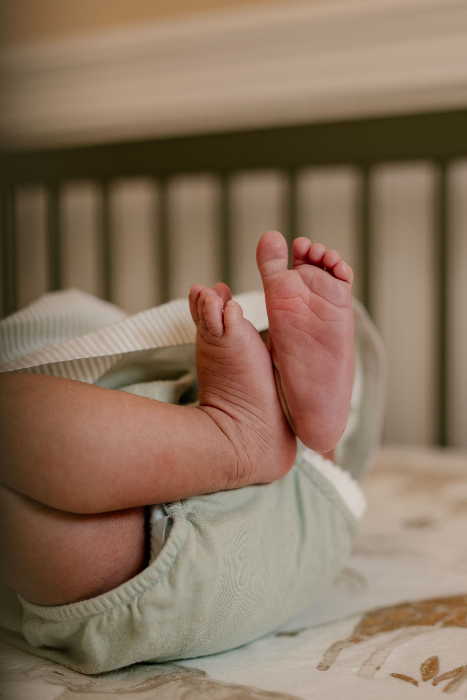 Close up detail shot of a newborn baby's feet while she lay in her green crib