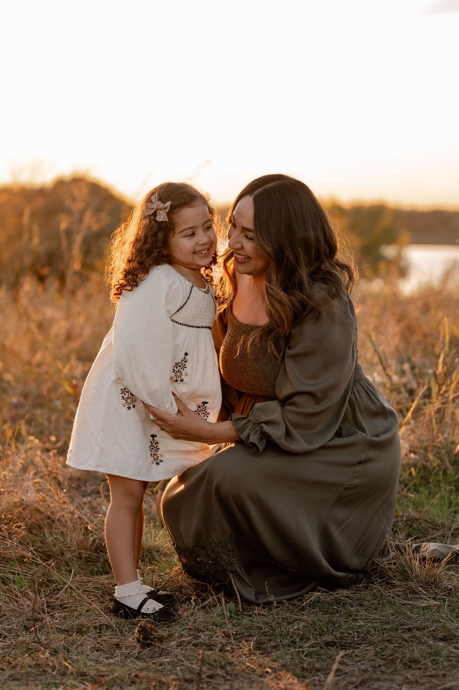Mother and daughter candidly embracing at golden hour overlooking the White Rock Lake in East Dallas, Texas