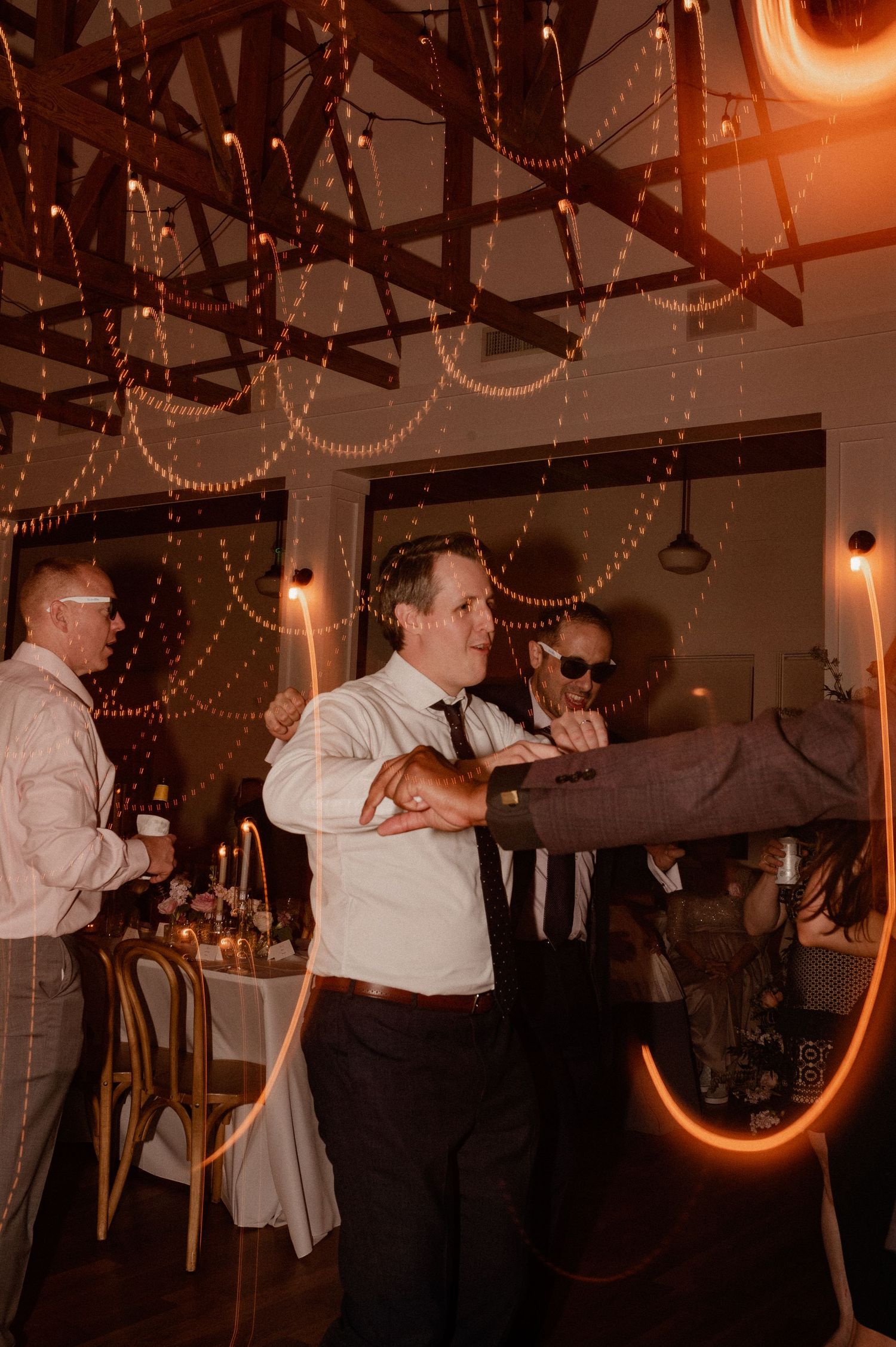 Wedding groom and guests dancing and celebrating under light trails