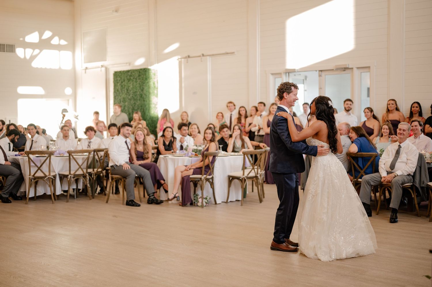 Candid moment of bride dancing with her father in a bright white reception venue during their father daughter dance in Plano, Texas