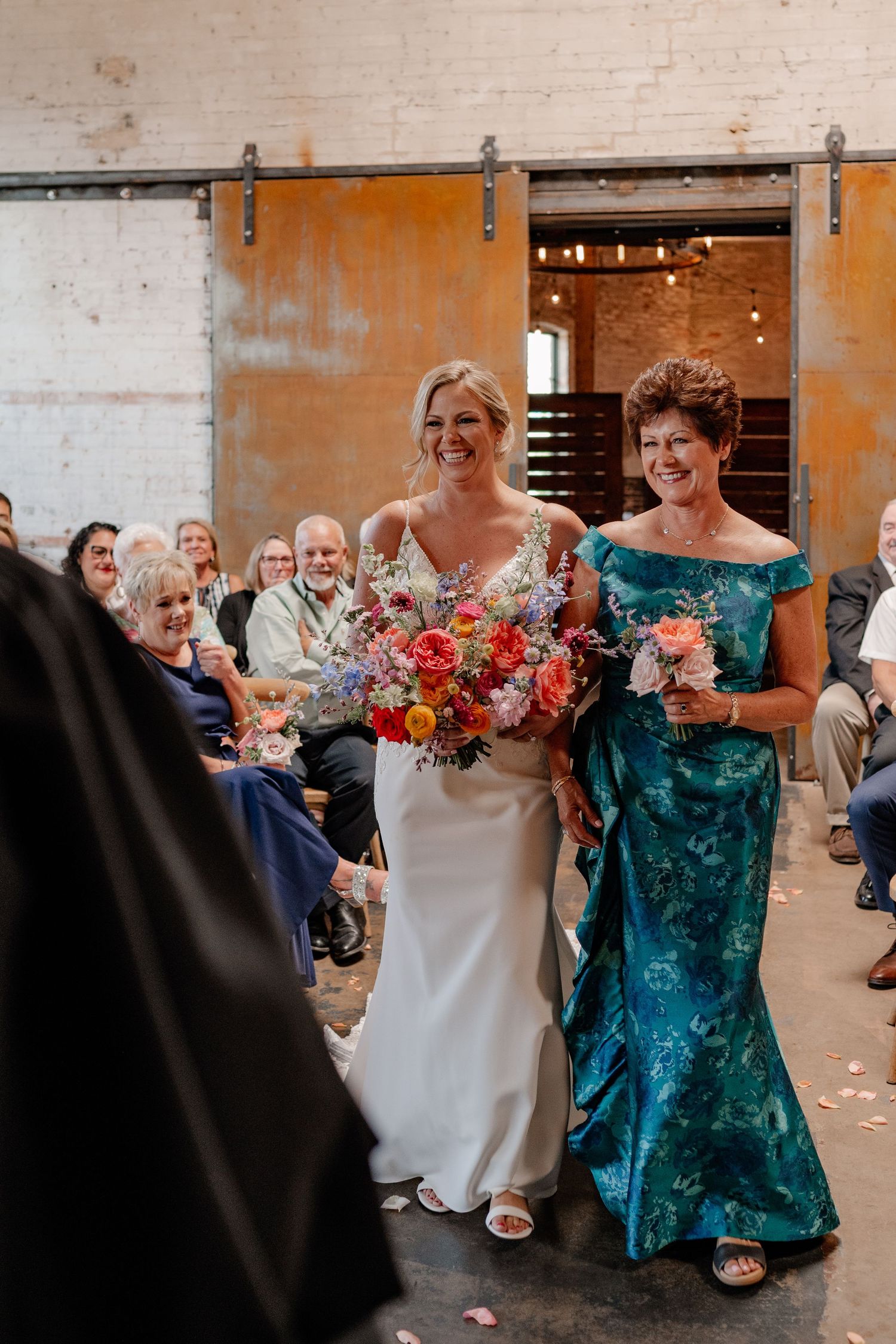 Joyful candid close-up of Bride and her mother coming down the aisle to her Groom in an indoor Summer wedding ceremony in Dallas, Texas