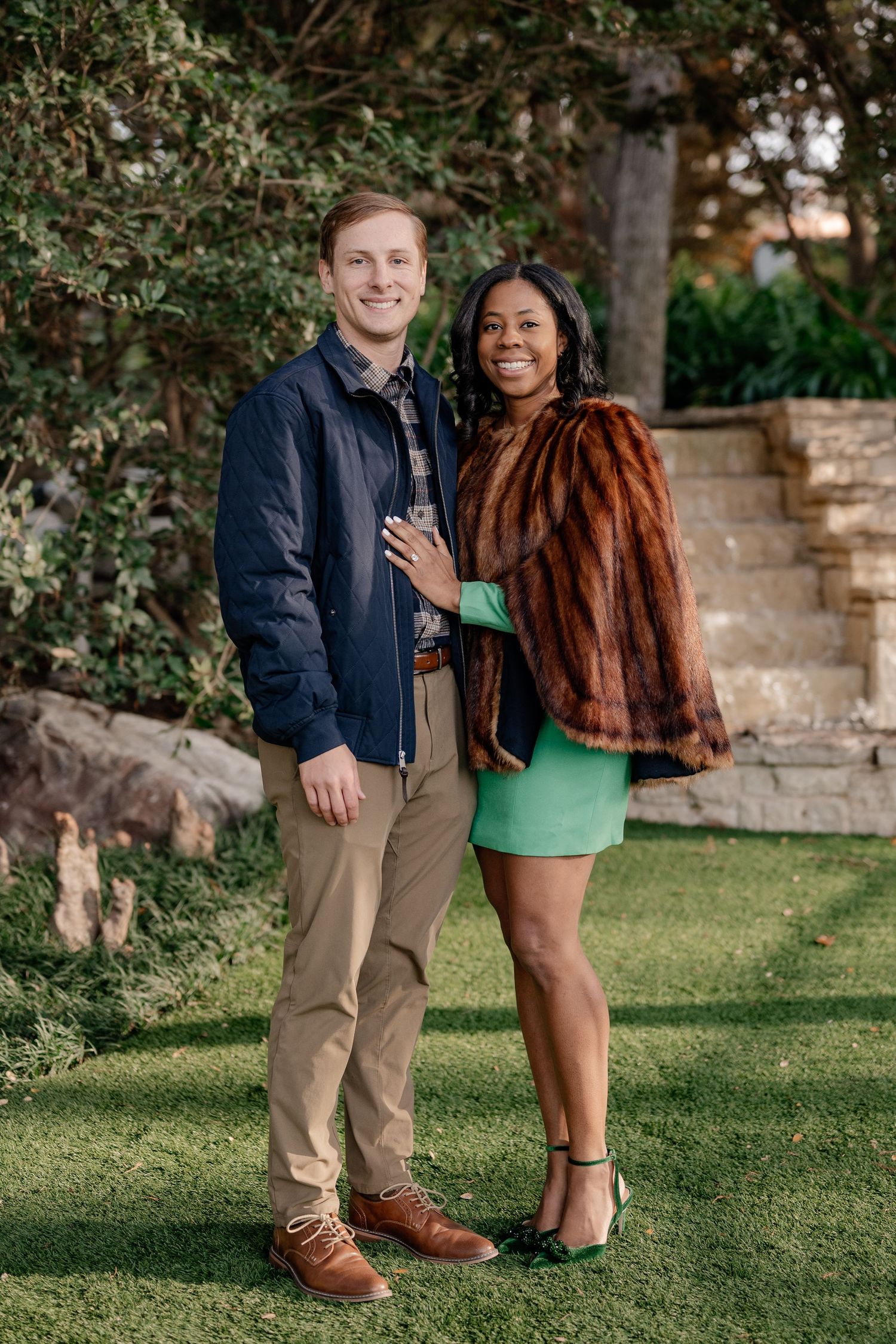Couple posing and showing off an engagement immediately after a winter proposal at the Dallas Arboretum