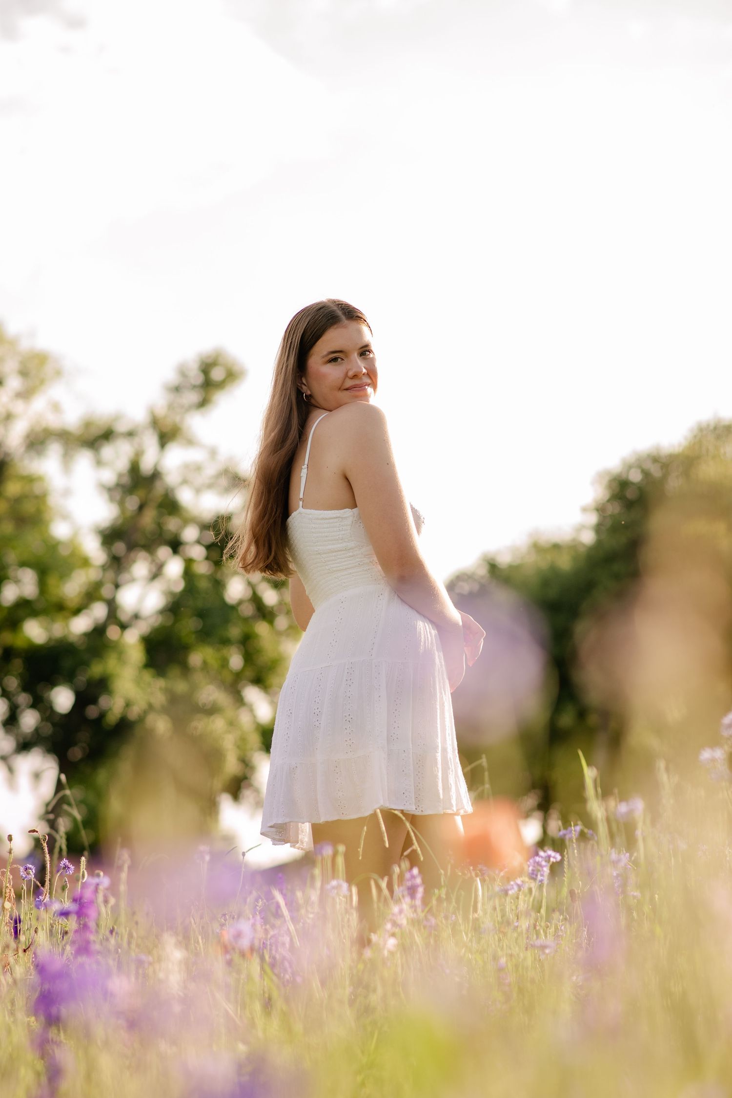 Senior girl casually posing in vivid wildflowers for a Spring senior photo session in Richardson, Texas