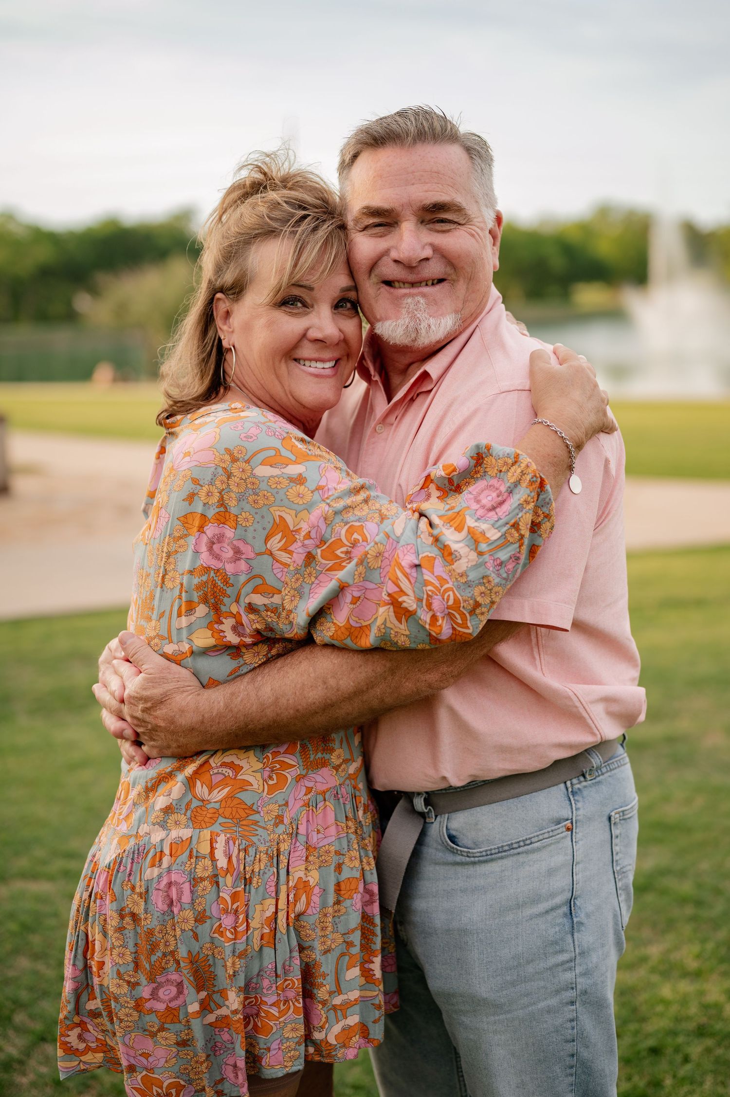 Married couple posing for Spring family photos in vivid colors at large park with water feature in Rockwall, Texas