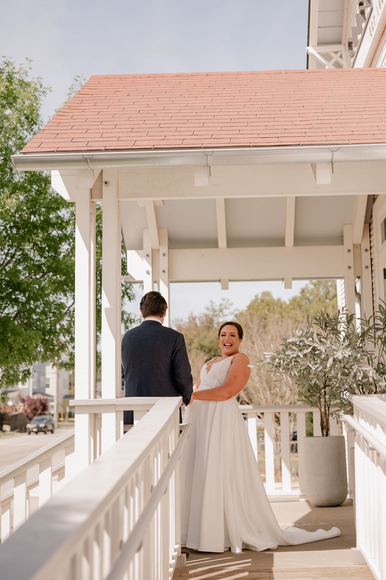 Wedding day first look between bride and groom showing natural reactions on a bright white veranda.