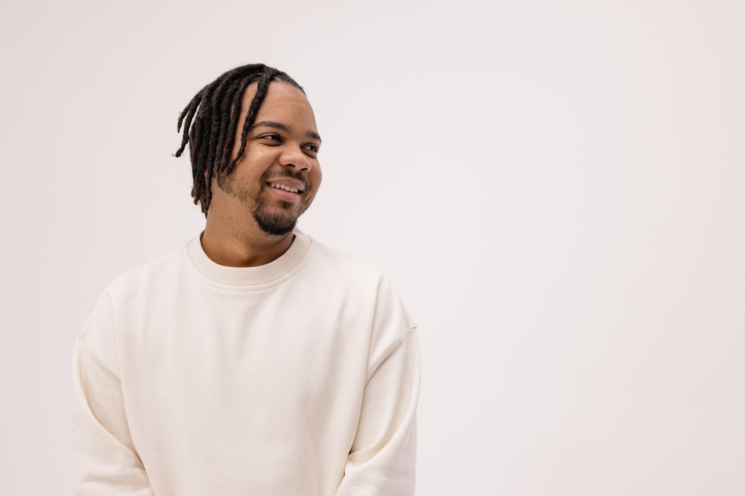 A playful headshot portrait of a male musician in front of a white studio wall