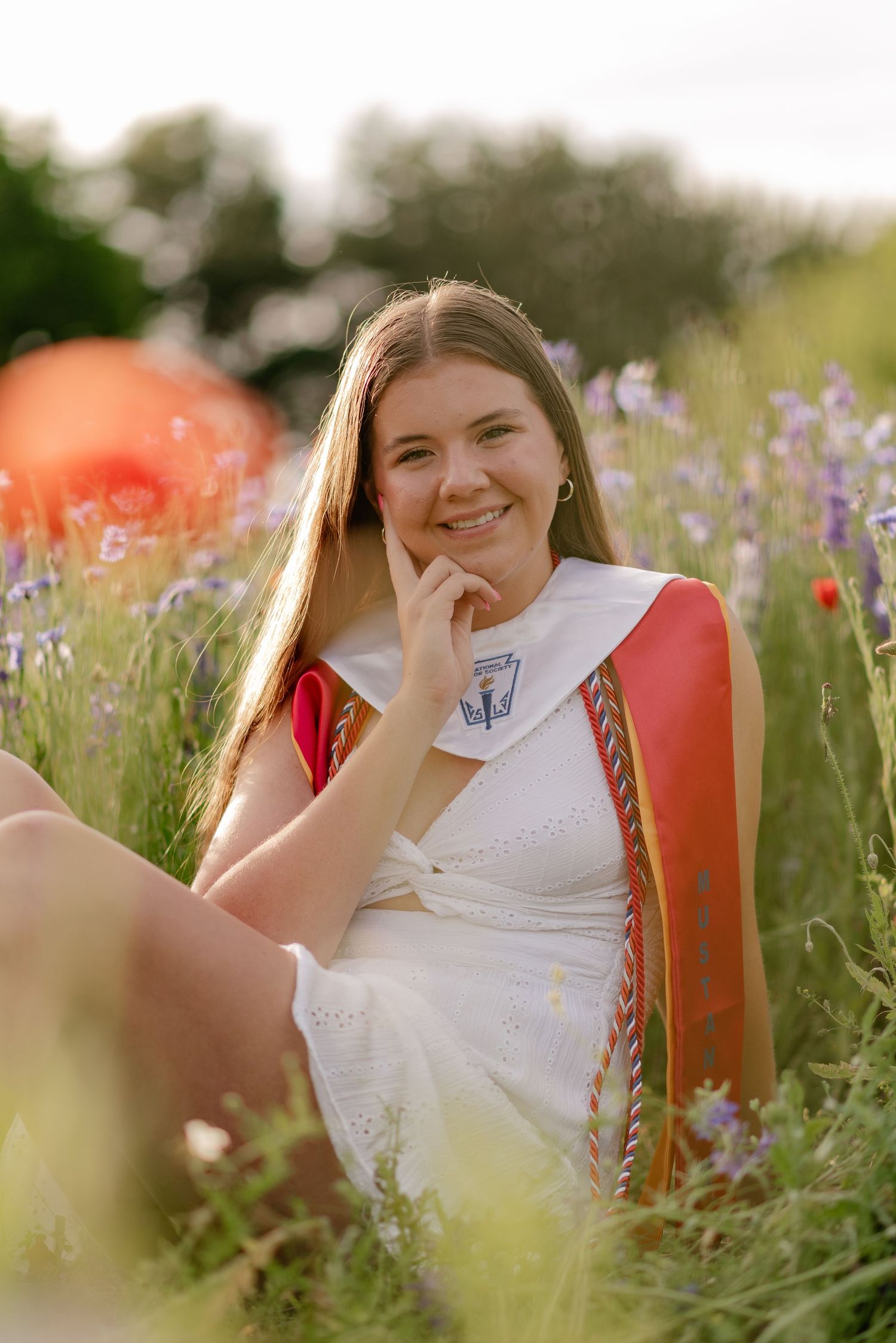 Senior girl casually posing in vivid wildflowers for a Spring senior photo session in Richardson, Texas
