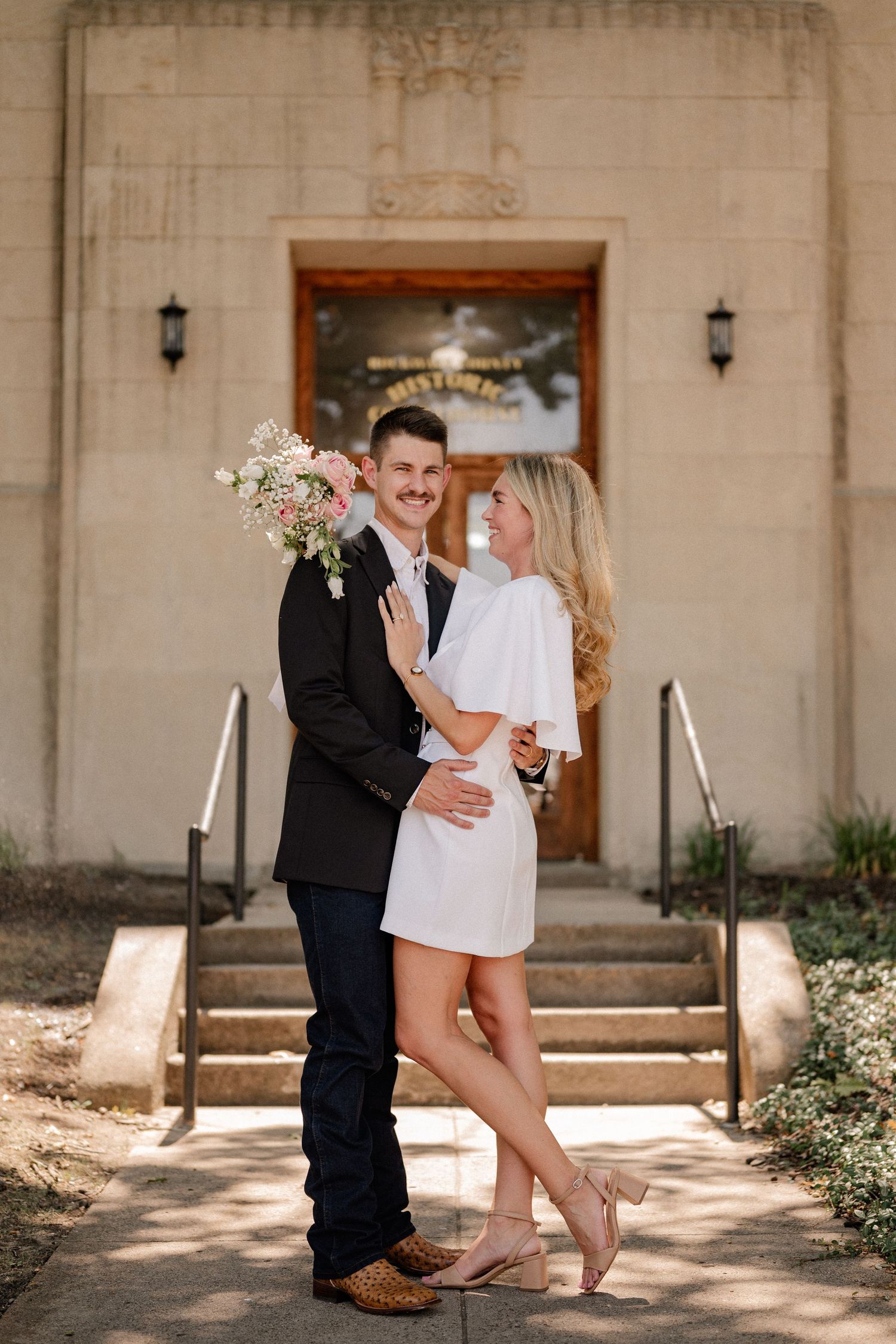 Married couple romantically embracing outside of the downtown Rockwall courthouse during elopement wedding photo session