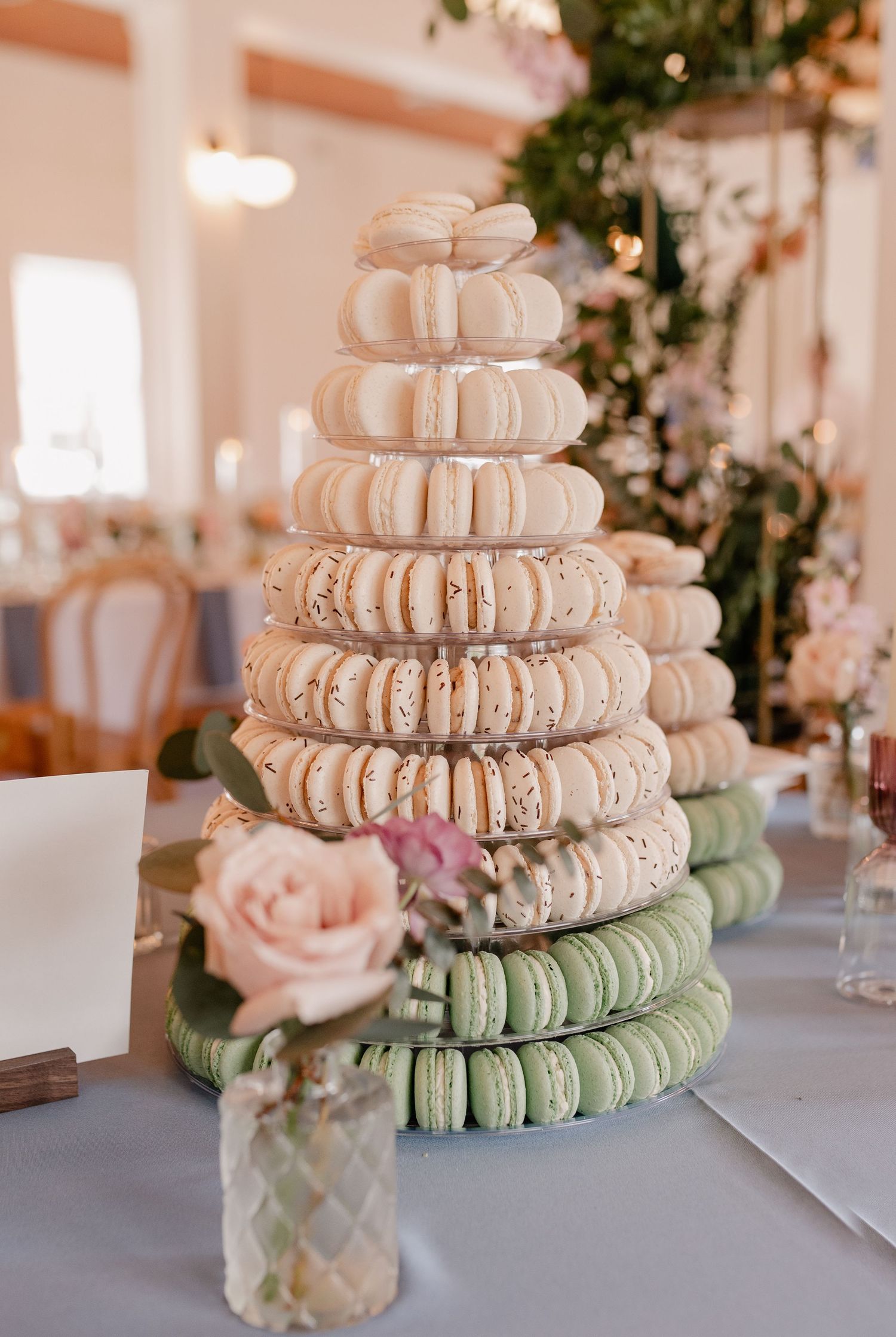 Tower of colorful macarons stacked in ombre pattern from white to mint green with pink rose accent at Dallas, TX wedding