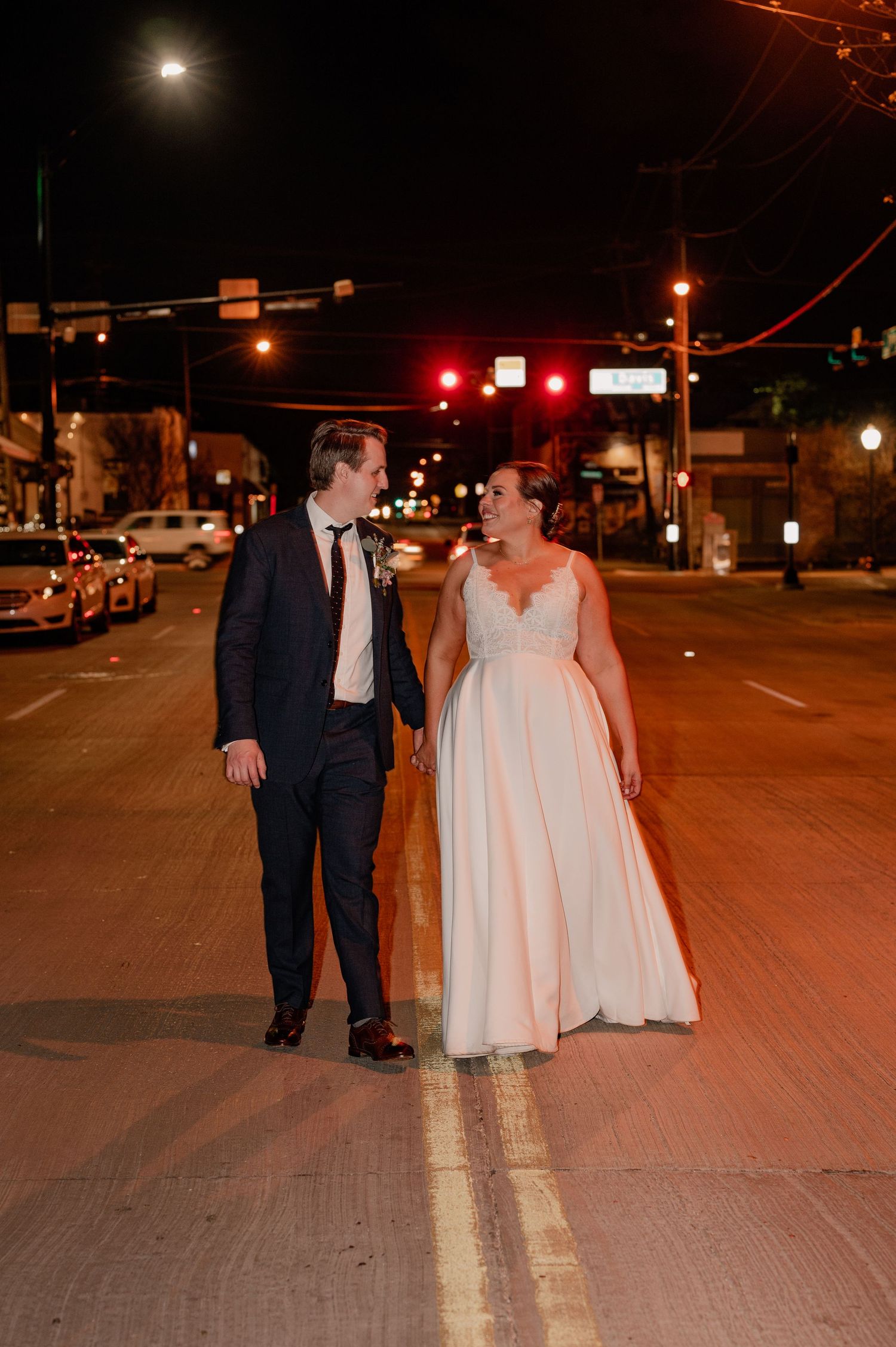 Couple takes romantic nighttime stroll on empty city street after their wedding in Bishop Arts, Dallas, Texas