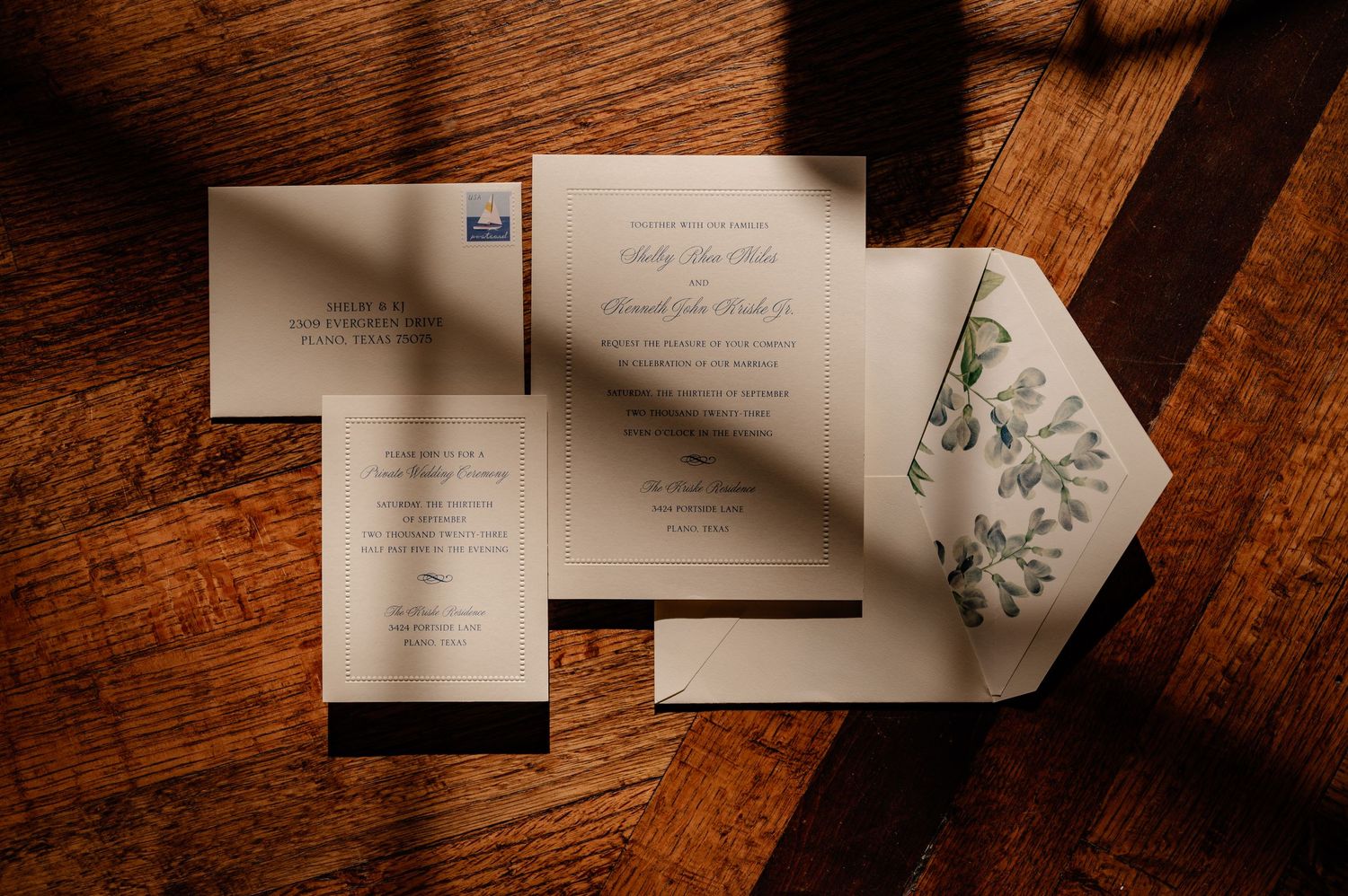 Elegant wedding invitations with floral designs laid out on a wooden surface.