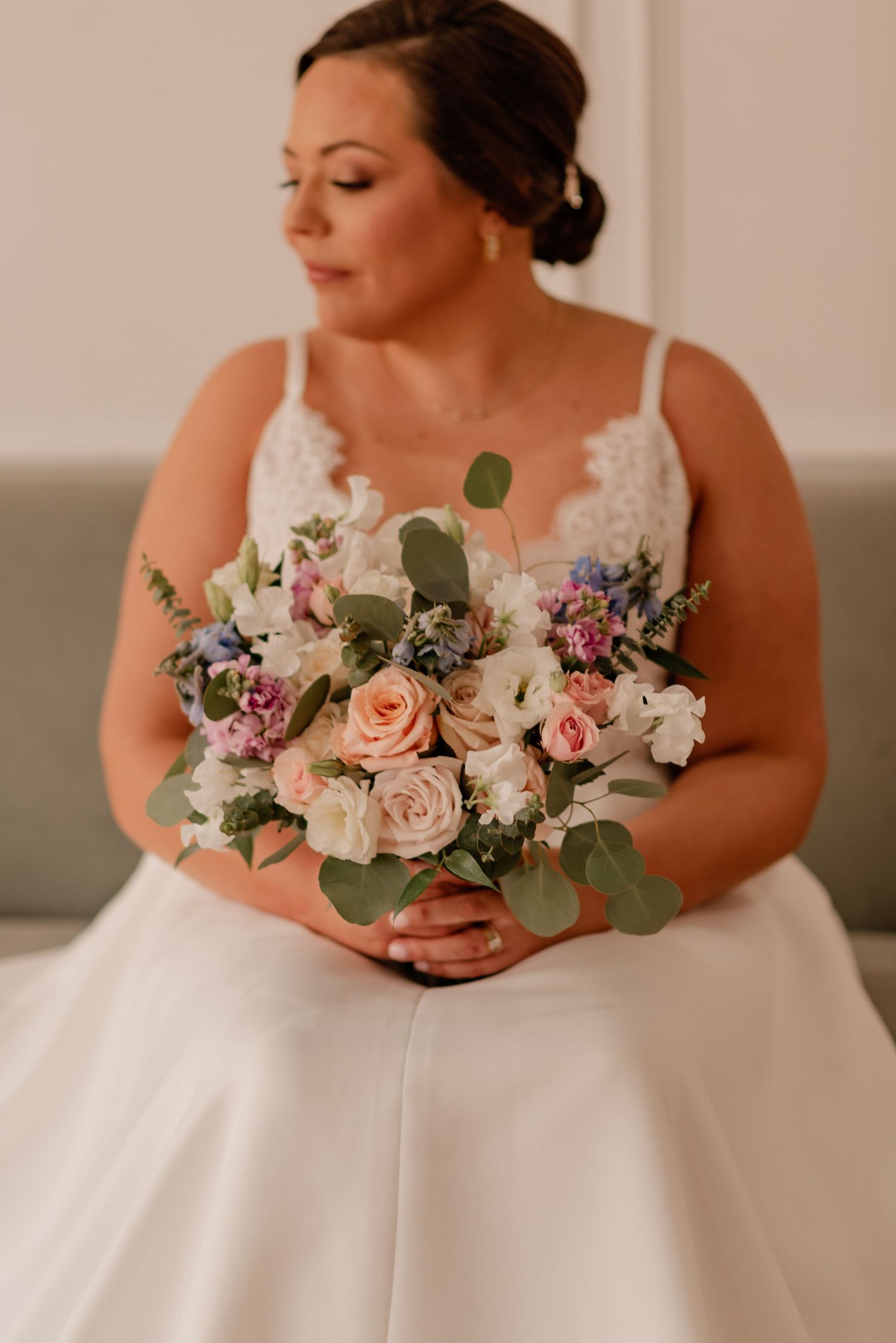 Wedding portrait showing elegant bridal bouquet with pink roses and white flowers against a classic white gown.
