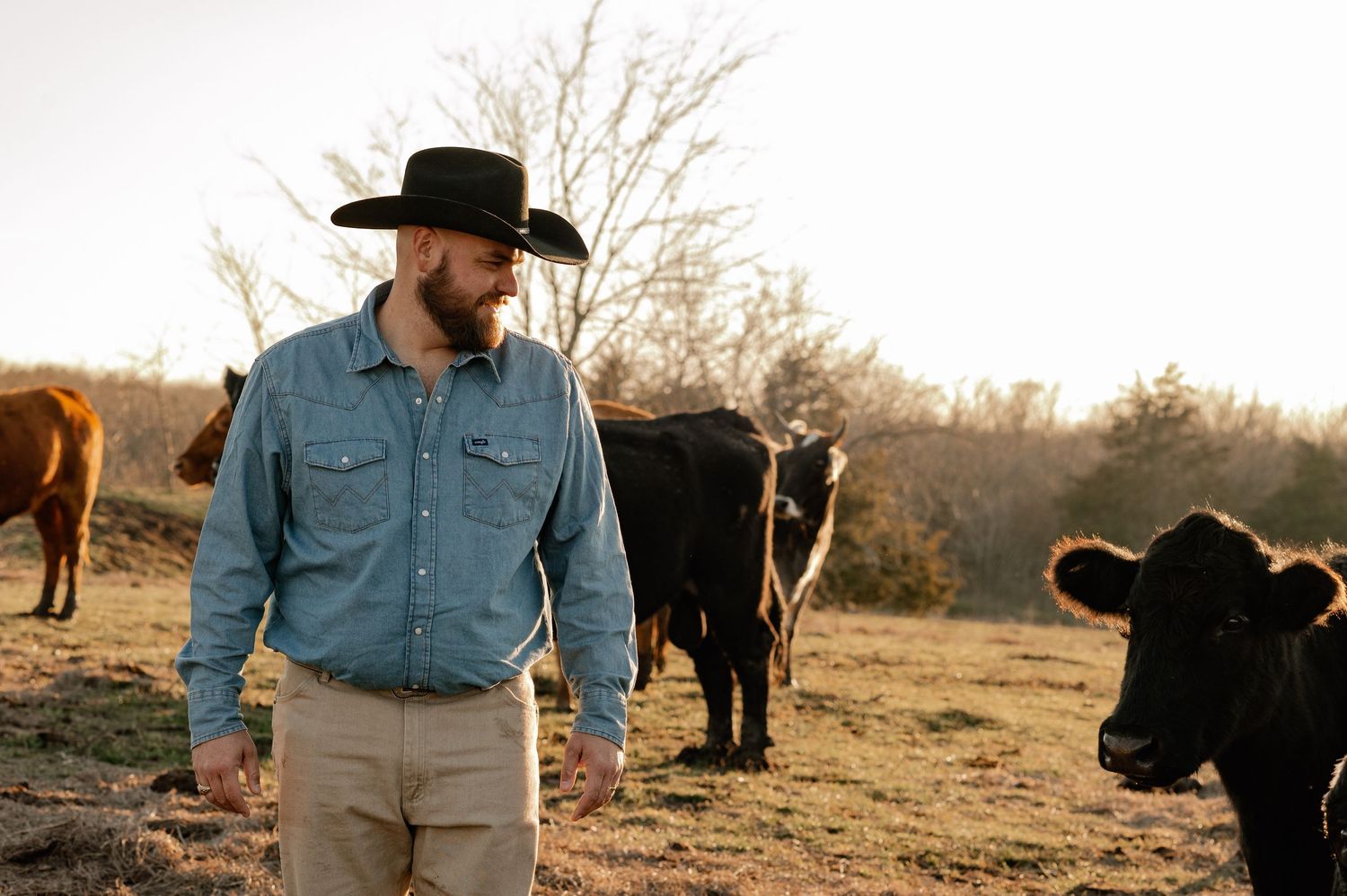 Man in cowboy hat overseeing his cattle on his cow farm in Rockwall, Texas during at at-home fall family session