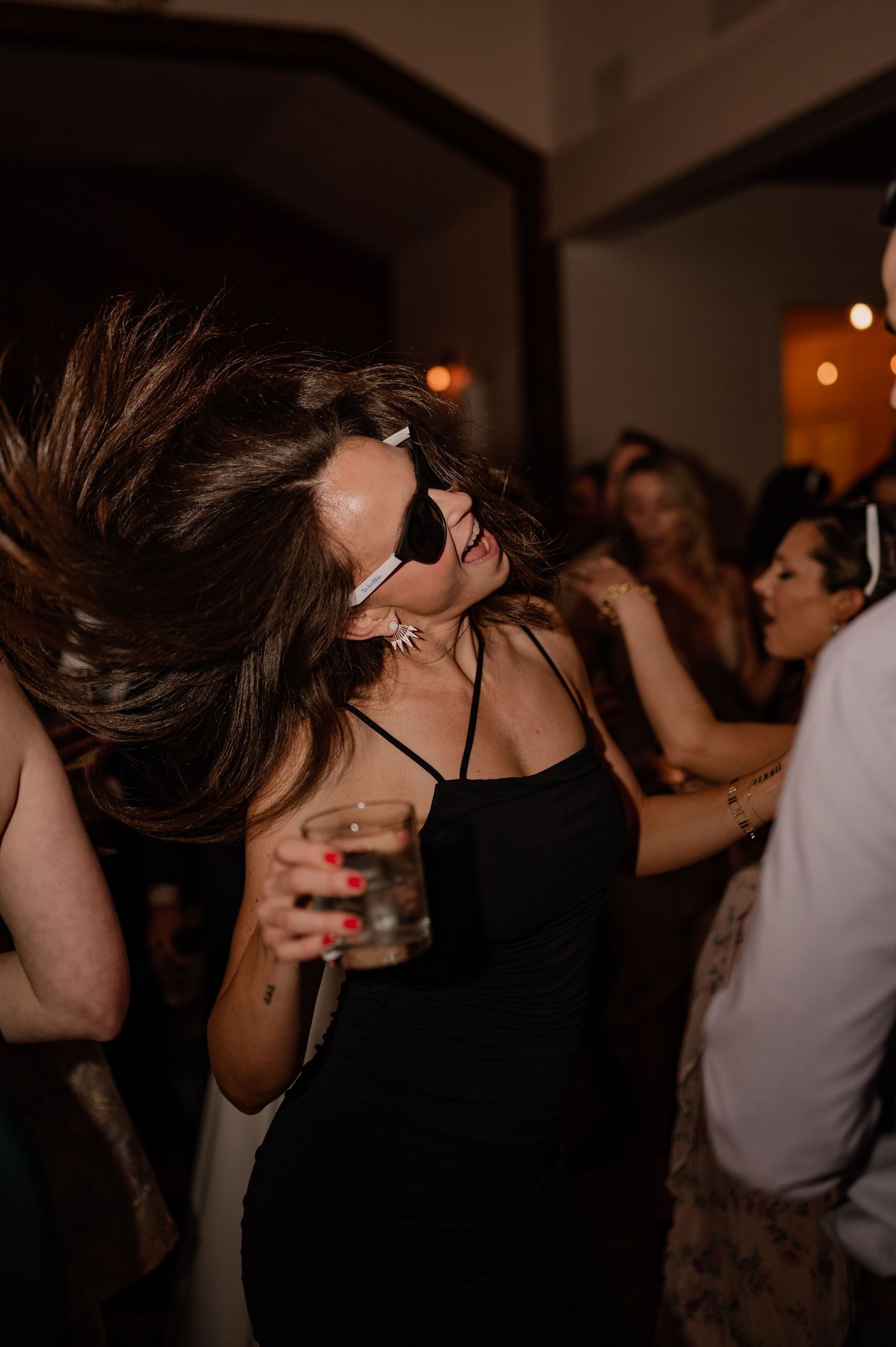 Guest dancing energetically at wedding reception with hair in motion.