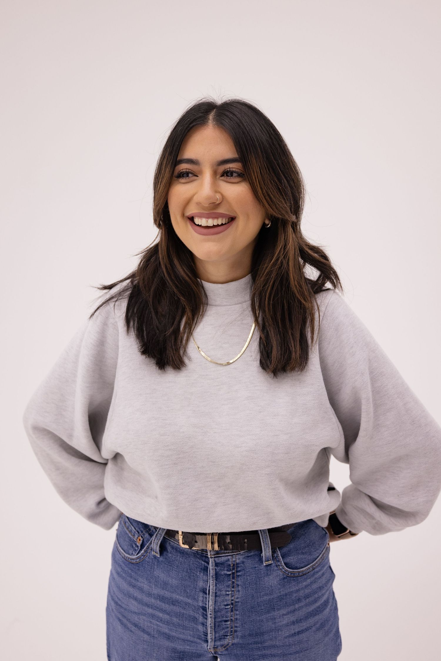 A joyful midshot headshot portrait of a female musician in front of a white studio wall