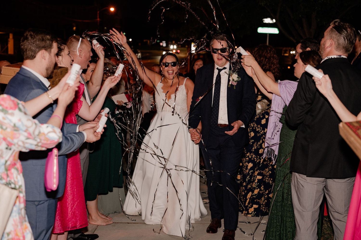 Guests line pathway with streamers as wedding couple makes their grand exit of Bishop Arts venue in Dallas, Texas