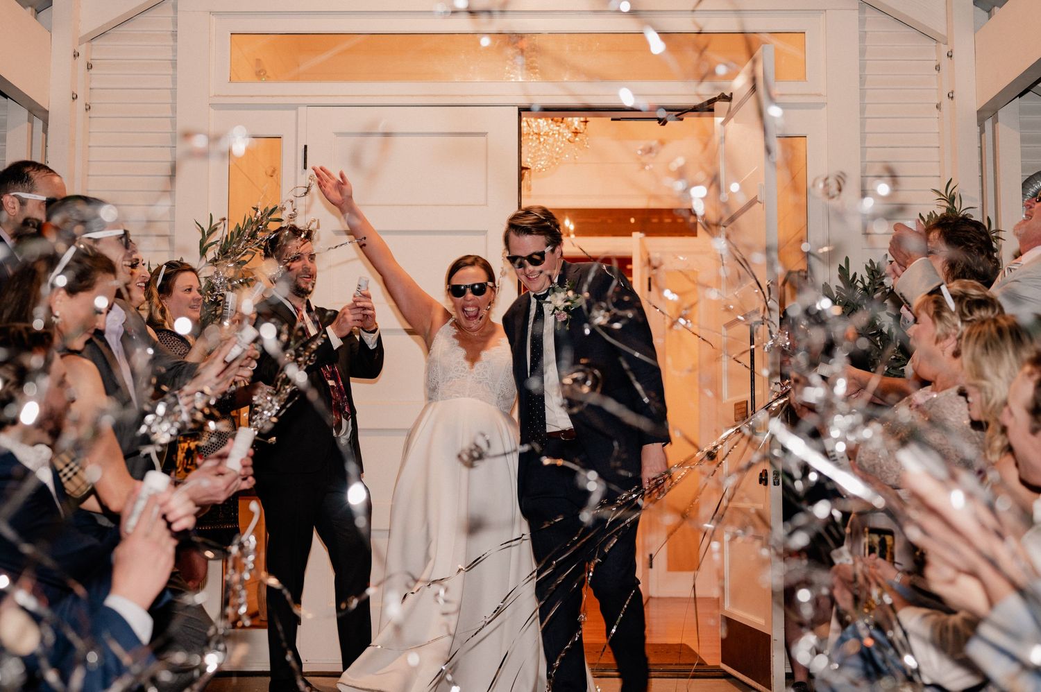 Joyful exit from wedding reception with guests popping streamers outside of Bishop Arts venue in Dallas, Texas